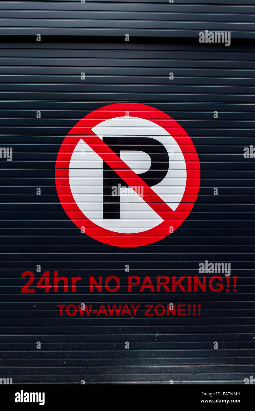 A sign on a garage door displays parking and access restrictions. Stock Photo