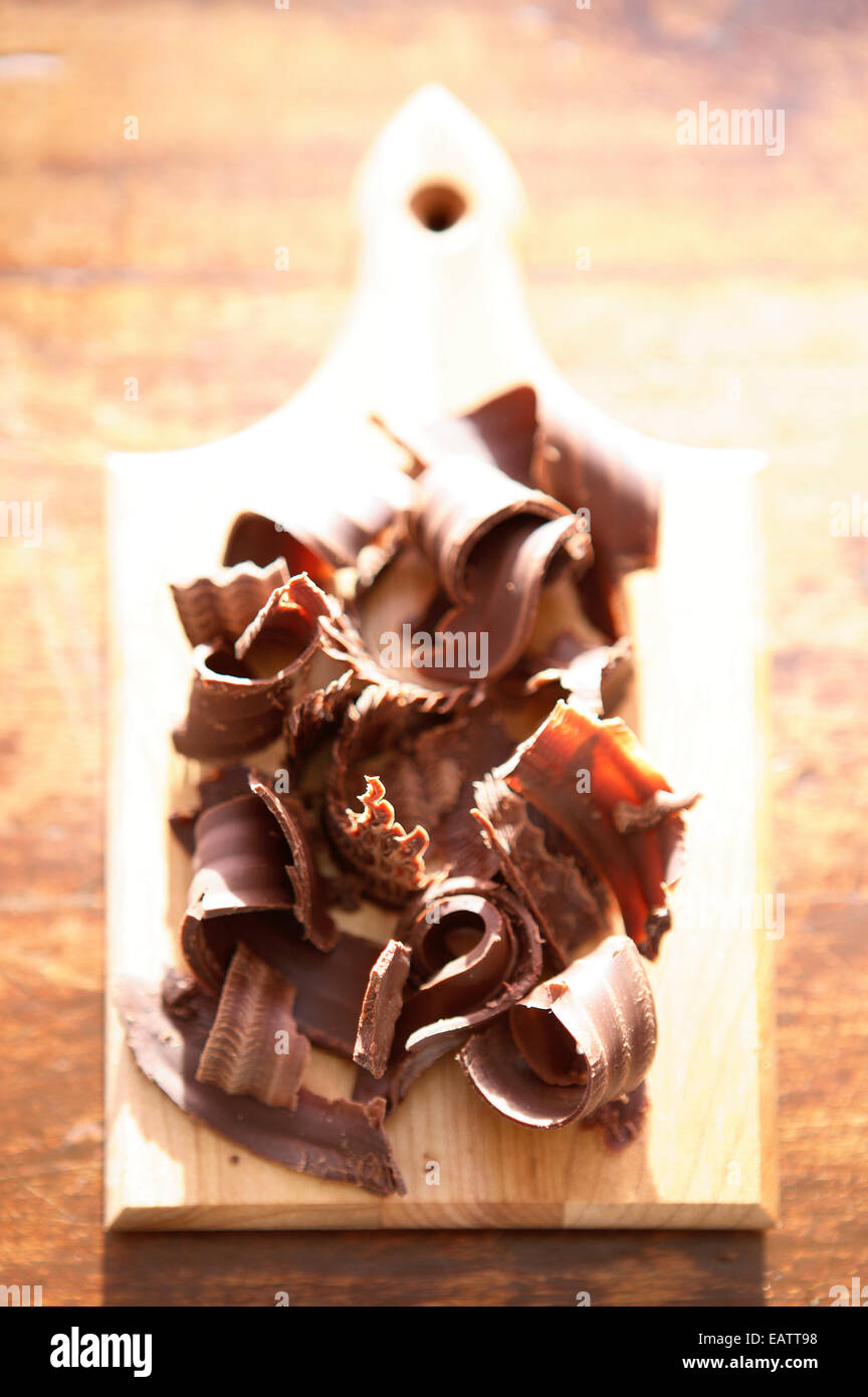 decorative chocolate shaving on a wood cutting board on a dark wood
