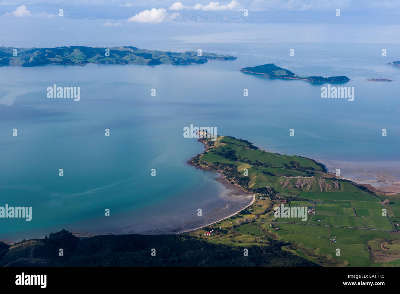 A peninsular dotted with lush farmland fingers into a turquoise bay. Stock Photo