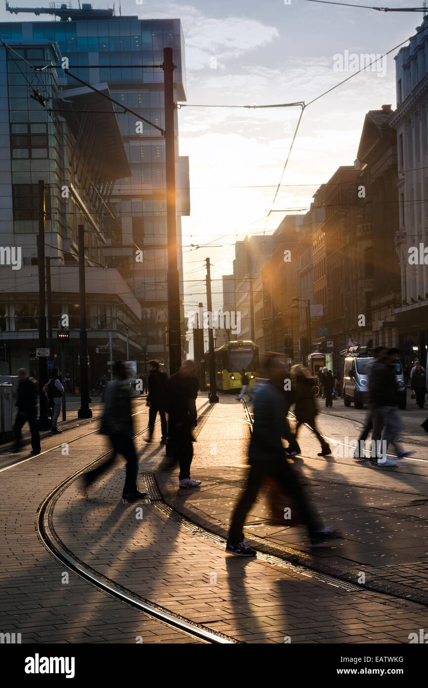 Manchester, Low evening winter sun in Fountain street, near Piccadilly Gardens, Shoppers silhouetted against the sun producing long shadows crossing the road as they enjoy a fine sunny end to the day in Manchester. Manchester Metrolink city centre tram lines & route. Stock Photo