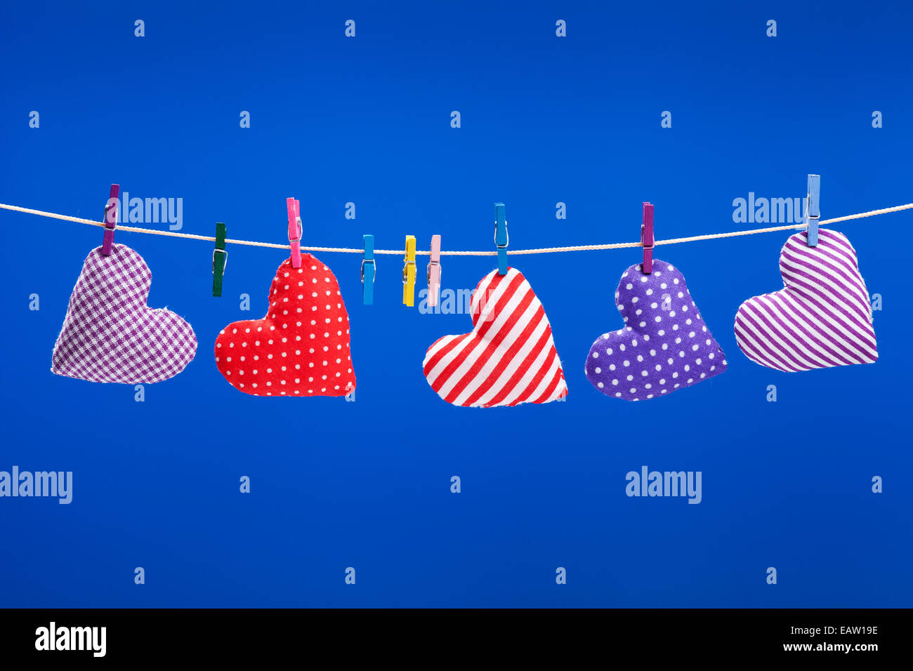 hearts hanging on a clothesline with clothespins, blue background Stock Photo