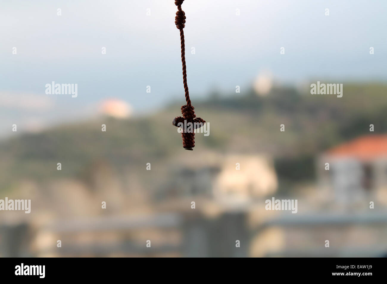 A hanging small knotted rosary with crucifix on a natural background. Stock Photo
