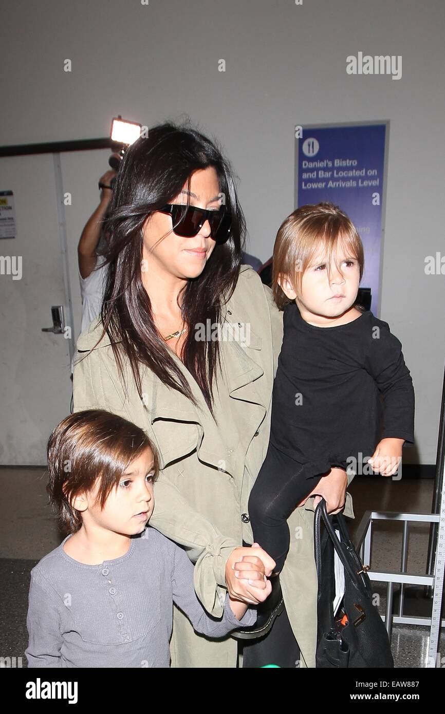 Kourtney Kardashian has her hands full carrying daughter Penelope Disick  and holding hands with son Mason Disick as they arrive at Los Angeles  International Airport (LAX) with a trolley full of luggage