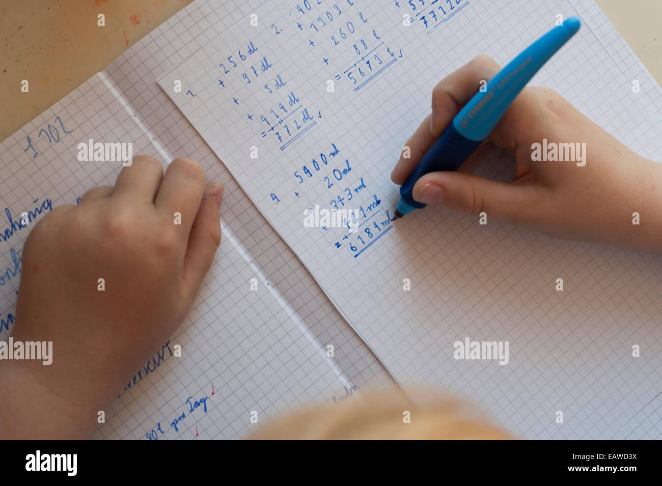a 10-year old schoolchild is doing his math homework. Stock Photo