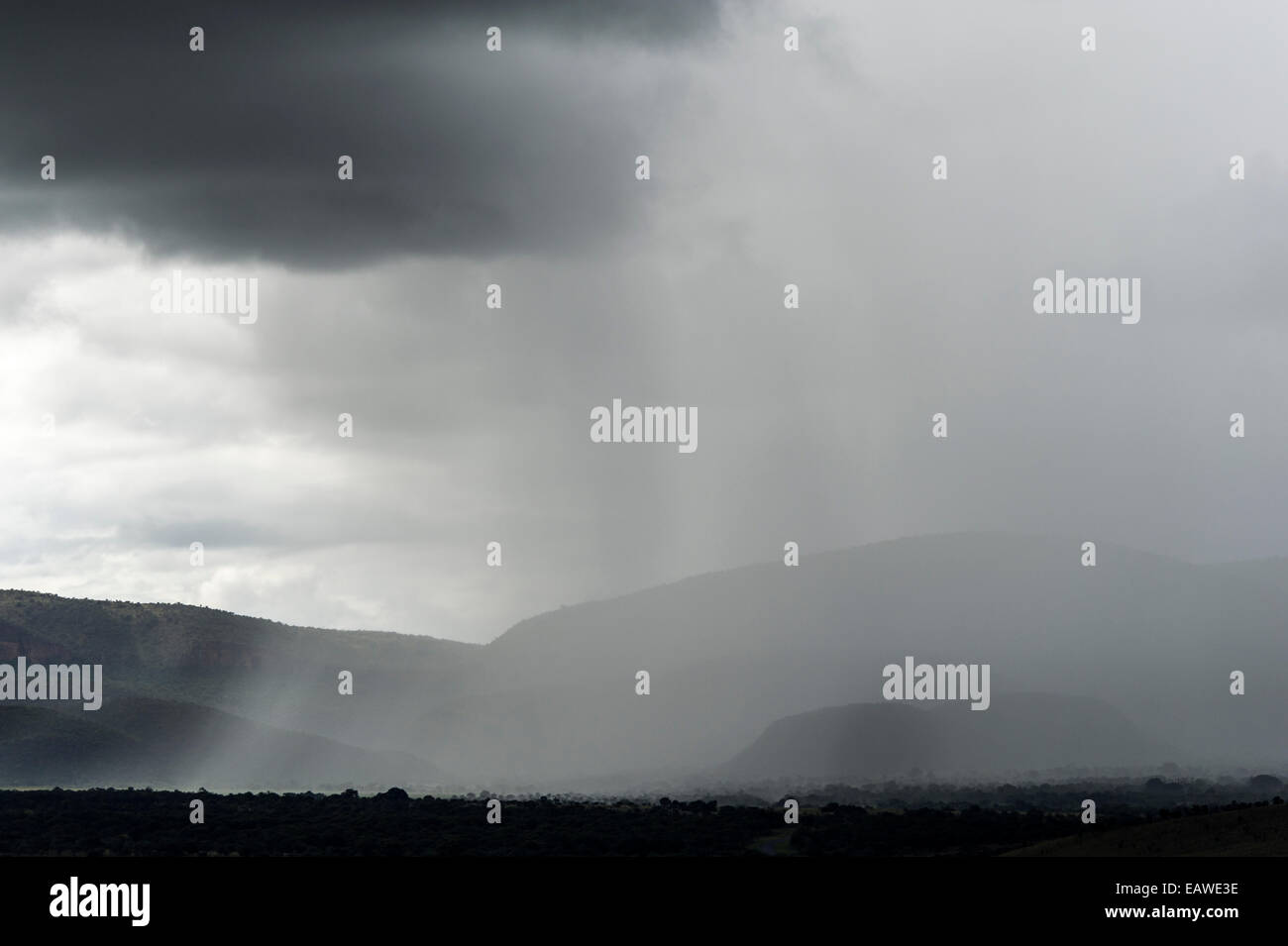 A torrential rainstorm shrouds rolling hills and farmland in grey. Stock Photo