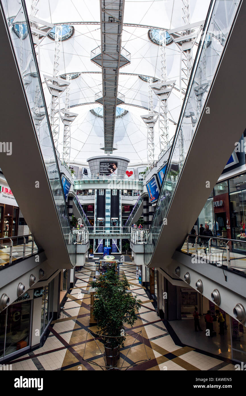 Enormous escalators connect levels in a sunlit shopping mall. Stock Photo