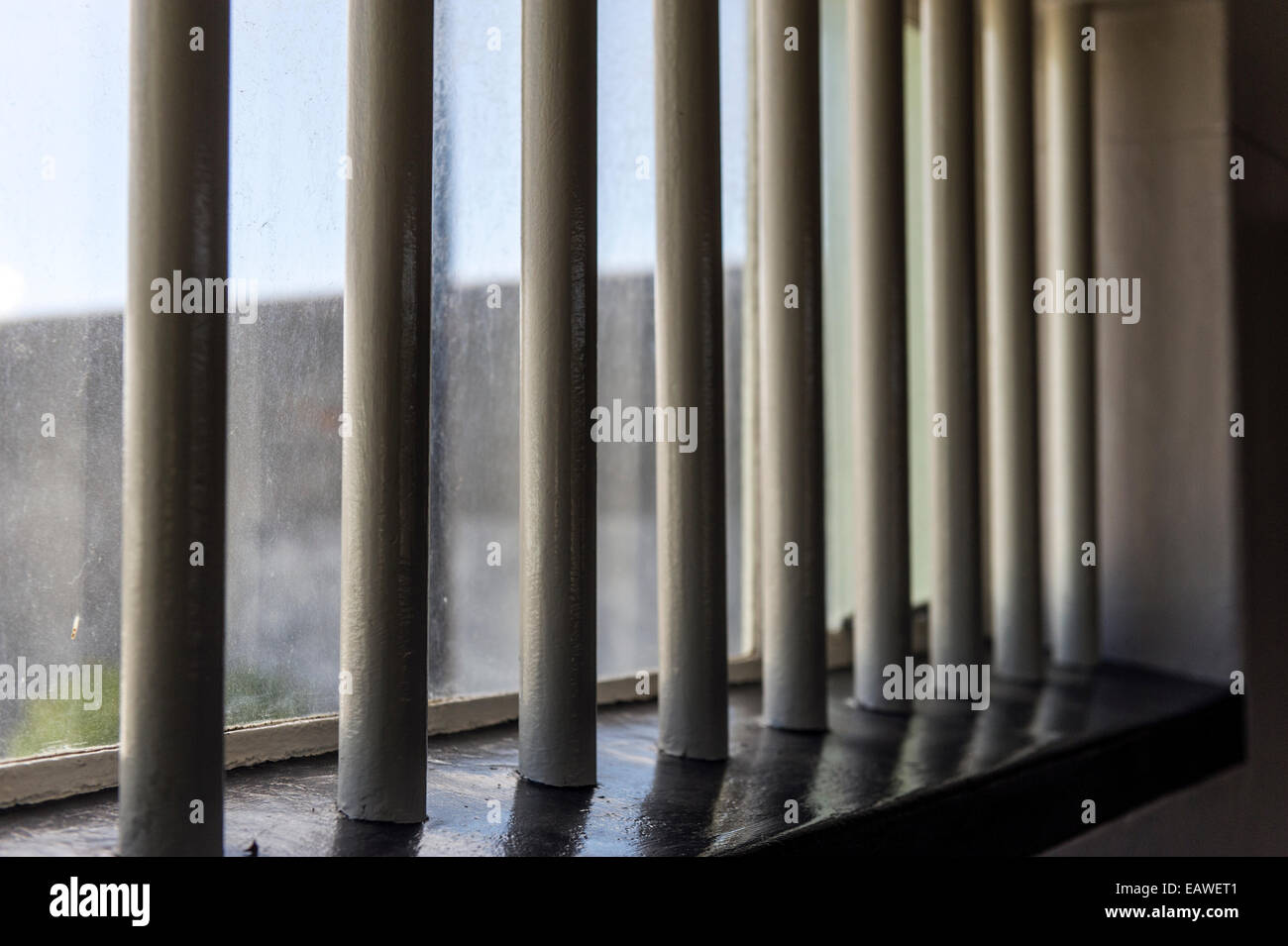 Sunlight catches stout steel bars in a prison cell. Stock Photo