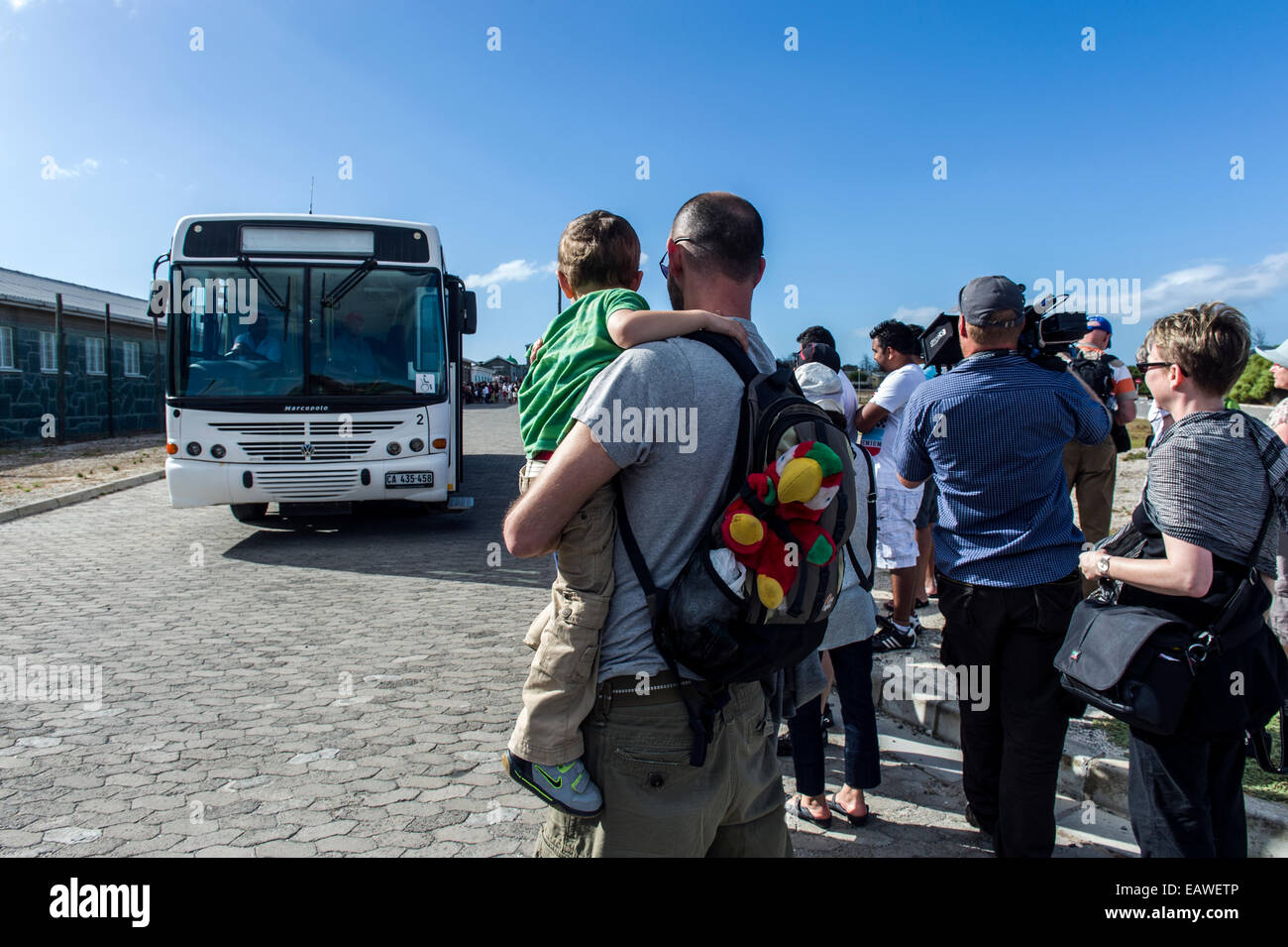 Tourists wait to board a bus for a tour of Robben Island prison. Stock Photo