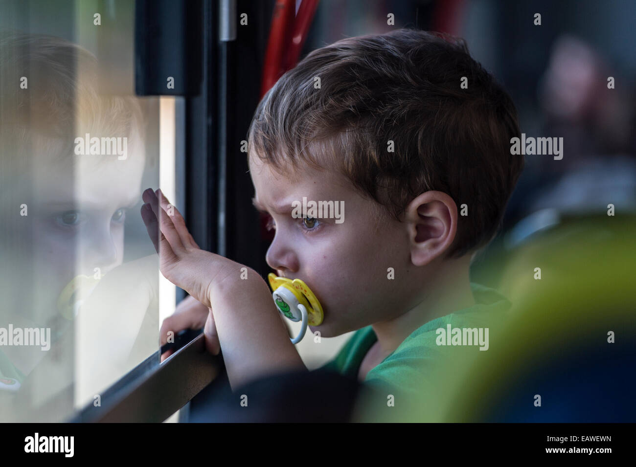 A small boy looks out of a bus window on a tour of a prison museum. Stock Photo