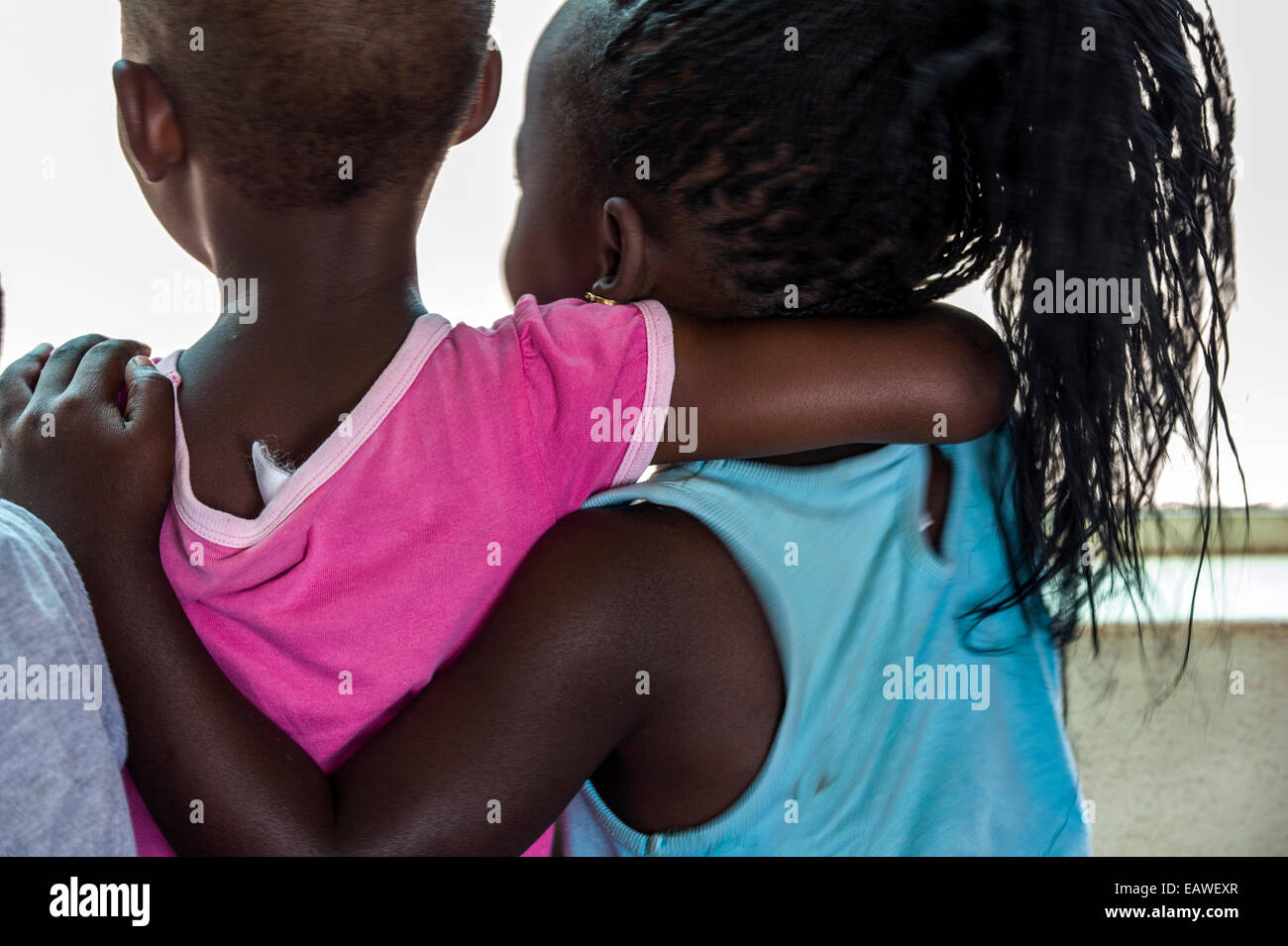 Two girls hug each other in friendship in an African Primary school. Stock Photo