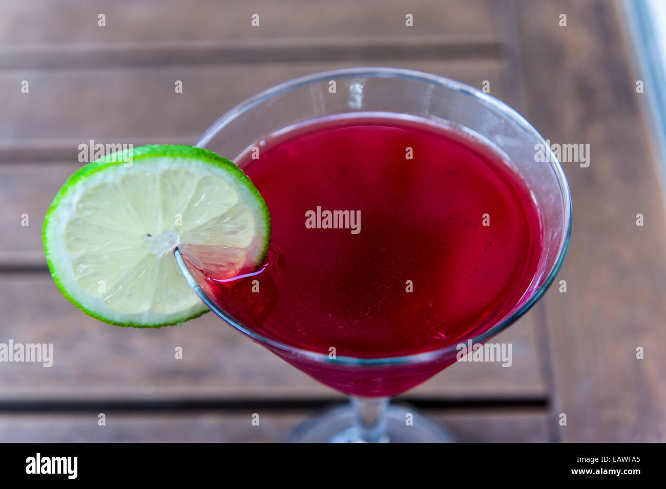 A raspberry cocktail with a slice of lime on the rim of the glass. Stock Photo