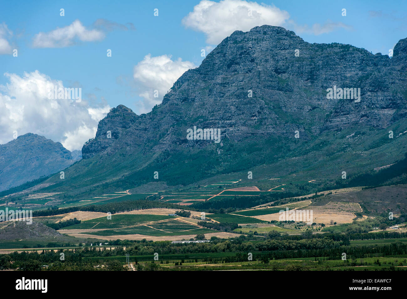 Rugged mountain peaks look down on rich farmland and vineyards. Stock Photo