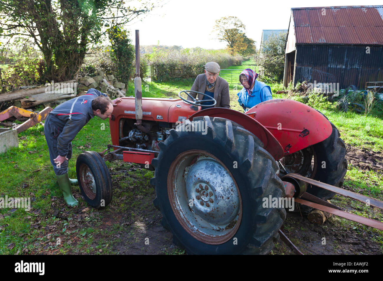 Cumbrian farmer Tom Brown, his wife Jean & son Gordon checking over a non-starting tractor on his farm at Irthington, Cumbria UK Stock Photo