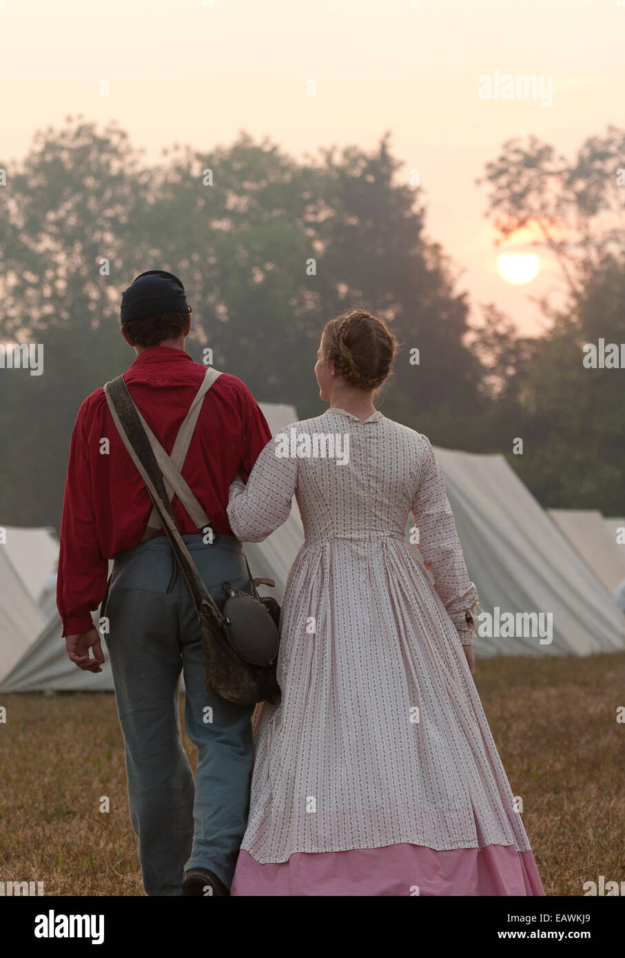 A young couple dressed in Civil War era clothing walk arm in arm. Stock Photo