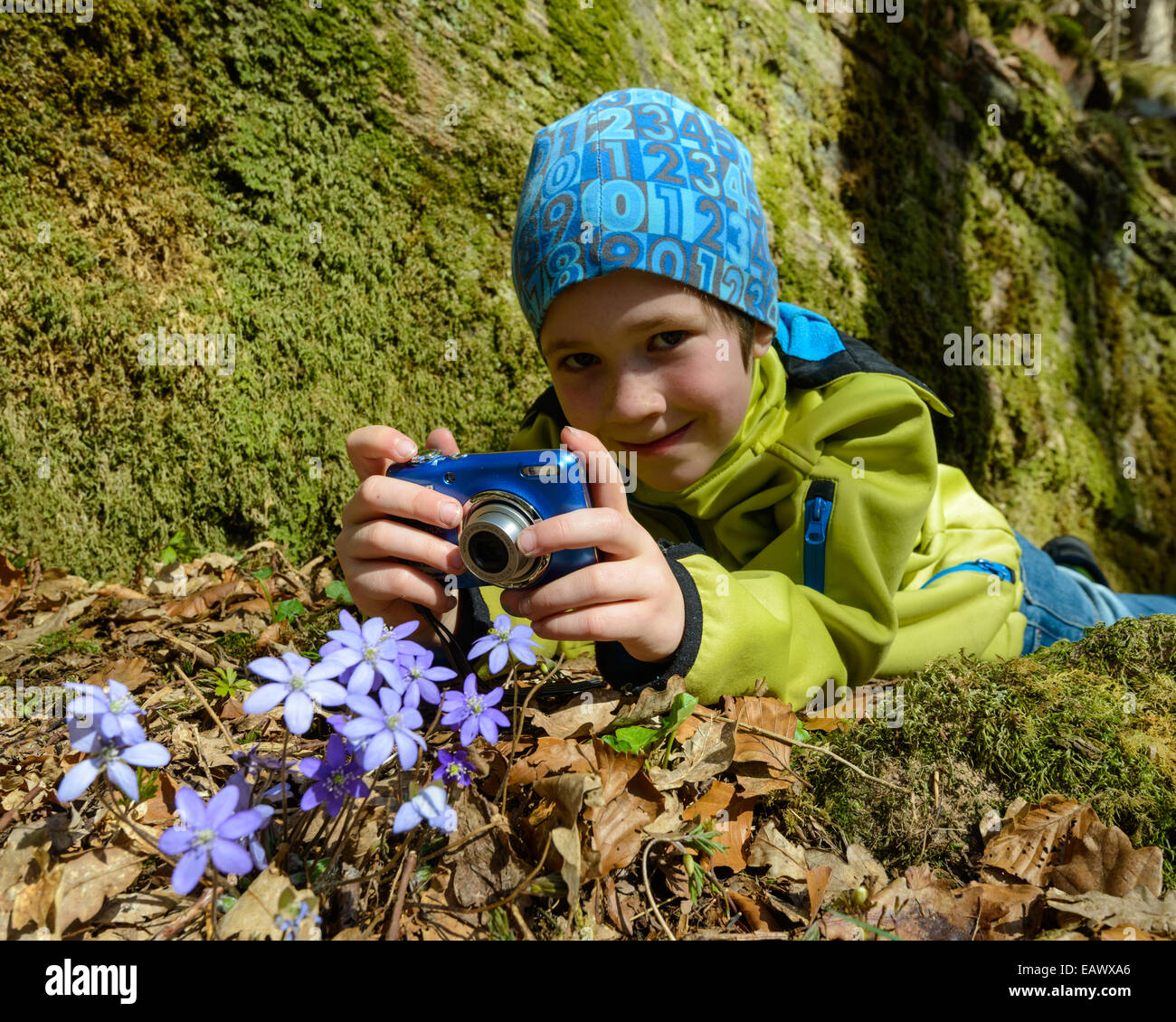 Young boy smiles while holding a blue digital camera Stock Photo