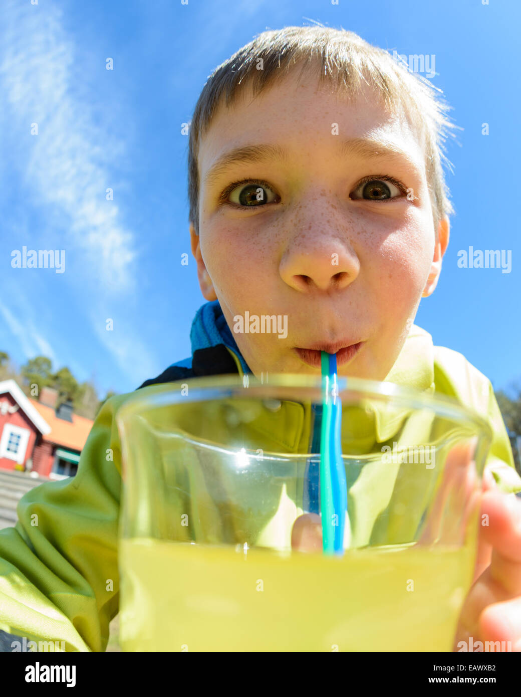 Young boy with wide eyes drinks juice with a straw Stock Photo