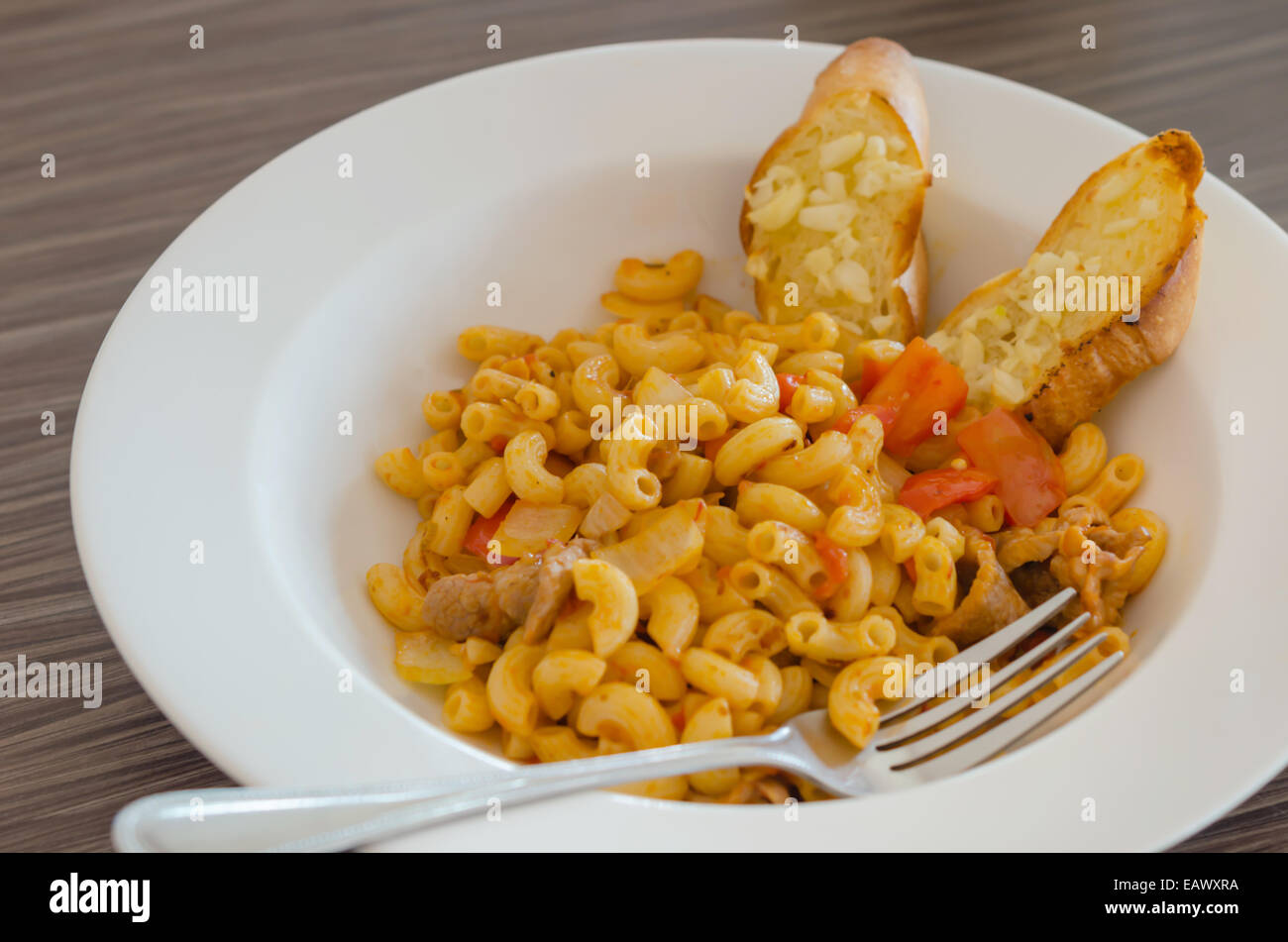 Italian tomato pasta served with garlic bread Stock Photo