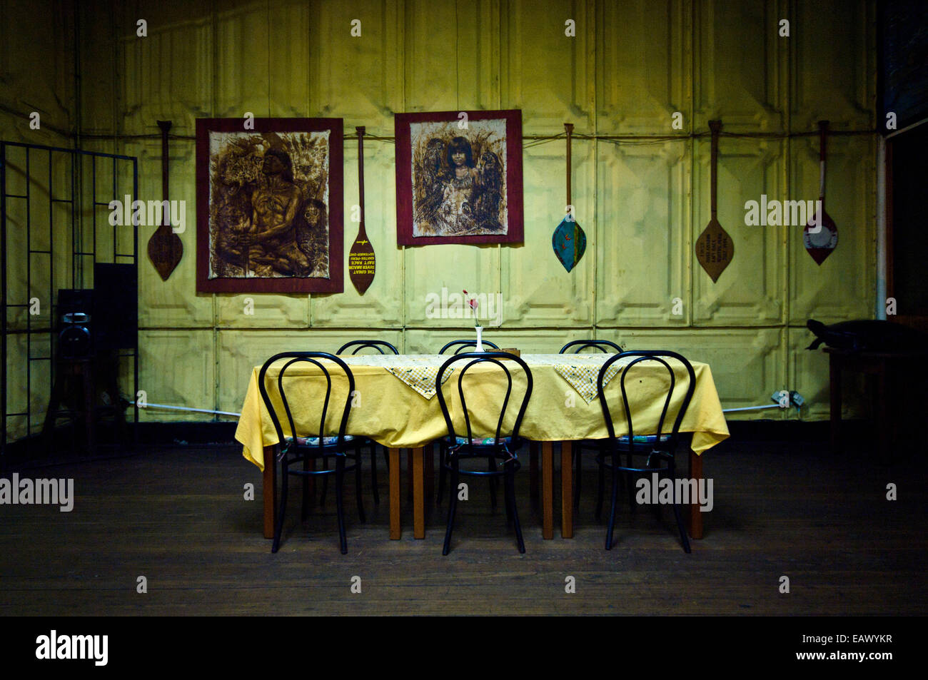 Indian canoe paddles line pressed steel walls above a dining table and