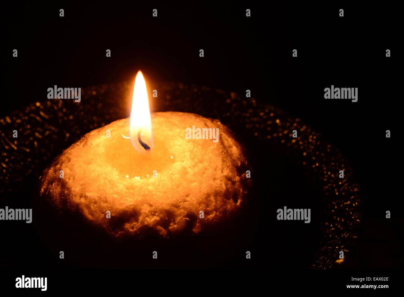 White candle on a plate burning on a black background Stock Photo Alamy