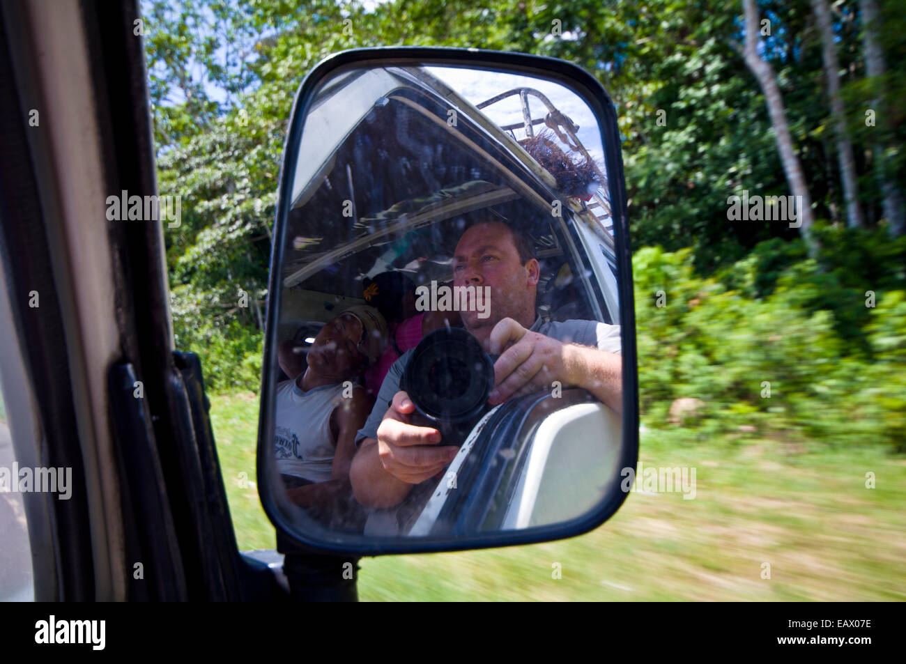 A photographer reflected in the rear view mirror of a taxi van Stock