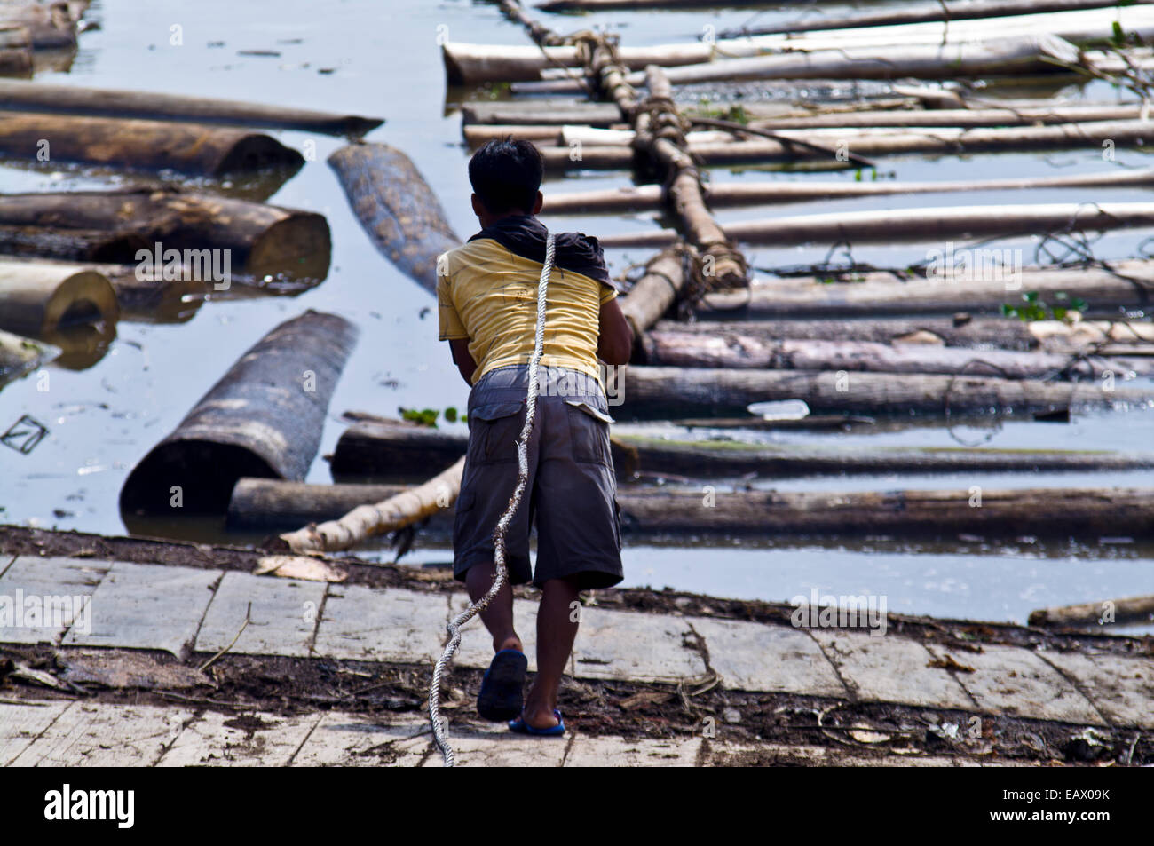 A laborer tows a heavy steel cable to the shore of the Amazon River to