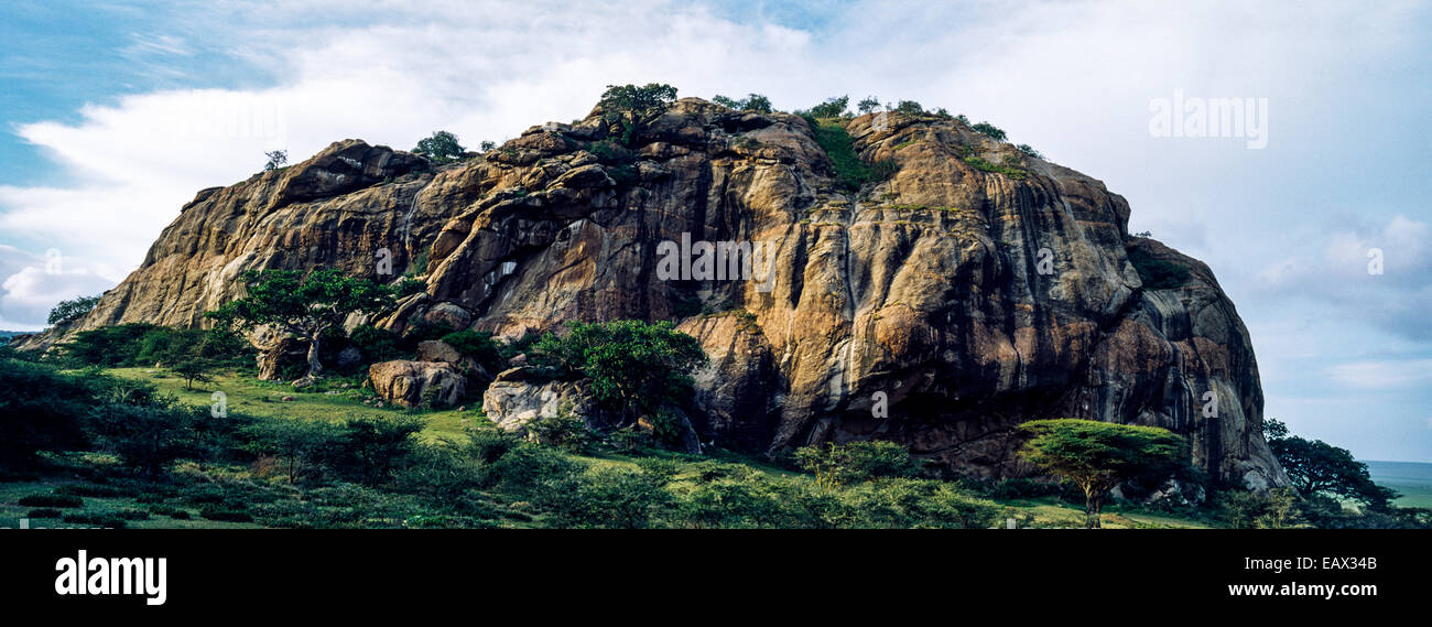 An enormous rocky outcrop rises from the savannah plain like a monolith. Stock Photo
