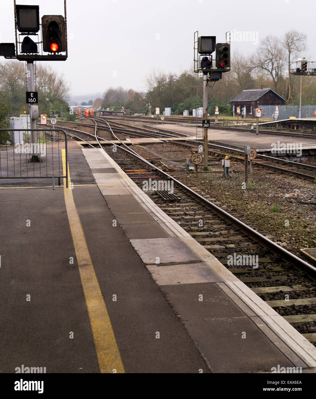 Red light at train station as railway maintenance workers in high visibility clothing carry out track work. Stock Photo