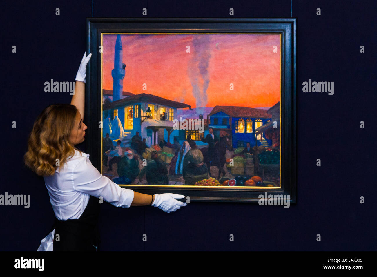 Sotheby's, London, November 21st 2014.  Sotheby's presents one of its strongest offerings of Russian paintings, icons and artworks as the renowned fine art  auction house celebrates its 25th year in Russia. Pictured: A sotheby's gallery technician straightens Boris Kustodiev's 'Bakhchisarai', and oil on canvas painting, described as the most impressive pre-revolutionary painting by Kustodiev to come to light in recent memory. It is expected to fetch between £1.2 and £1.8 million at auction. Credit:  Paul Davey/Alamy Live News Stock Photo