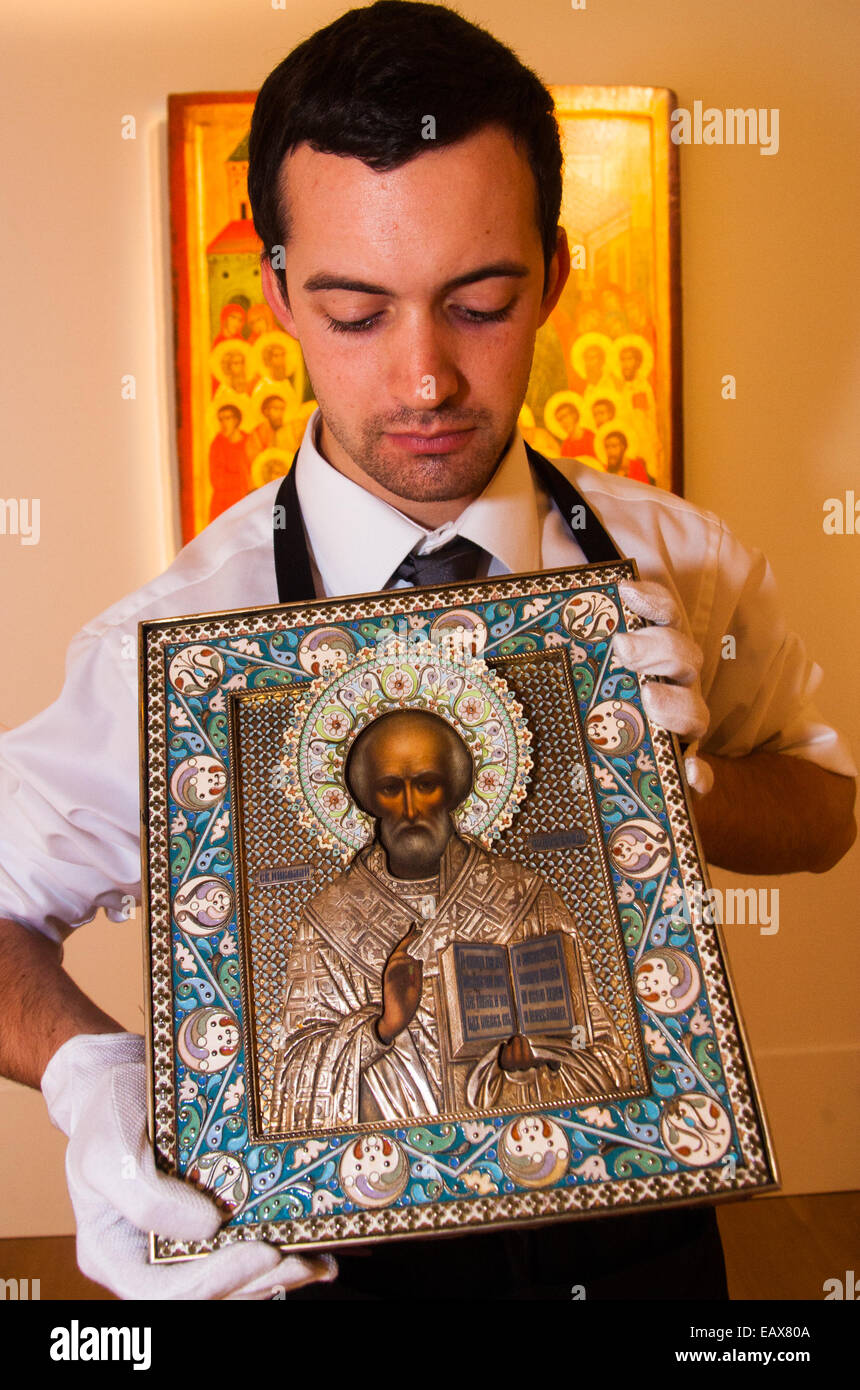Sotheby's, London, November 21st 2014.  Sotheby's presents one of its strongest offerings of Russian paintings, icons and artworks as the renowned fine art  auction house celebrates its 25th year in Russia. Pictured: A gallery technician  holds a silver-gilt and cloisonne enamel icon of St Nicholas the Miracleworker, expected to fetch between £50,000 - 70,000 at auction. Credit:  Paul Davey/Alamy Live News Stock Photo