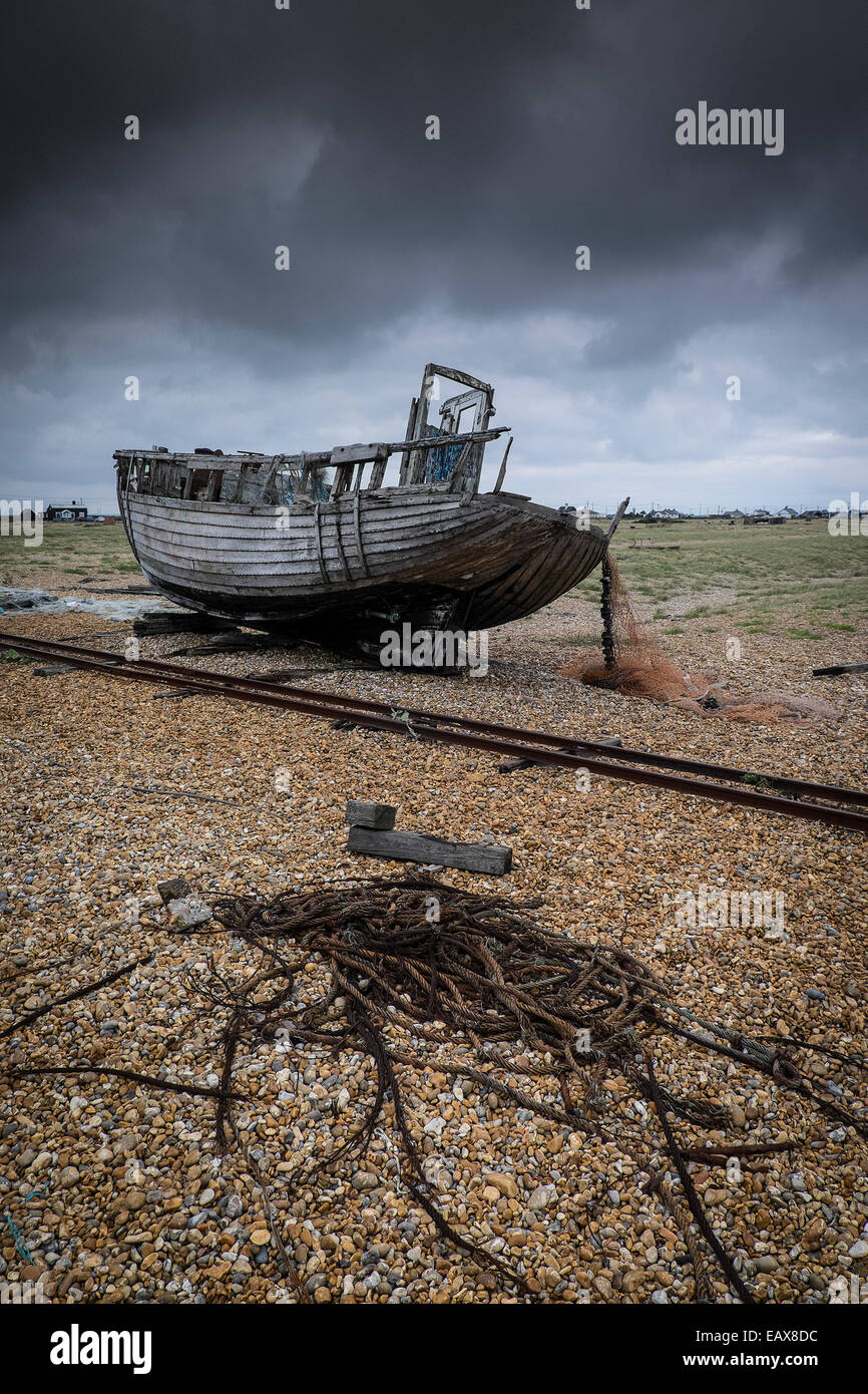 An old wooden fishing boat abandoned on the beach at Dungeness in Kent ...