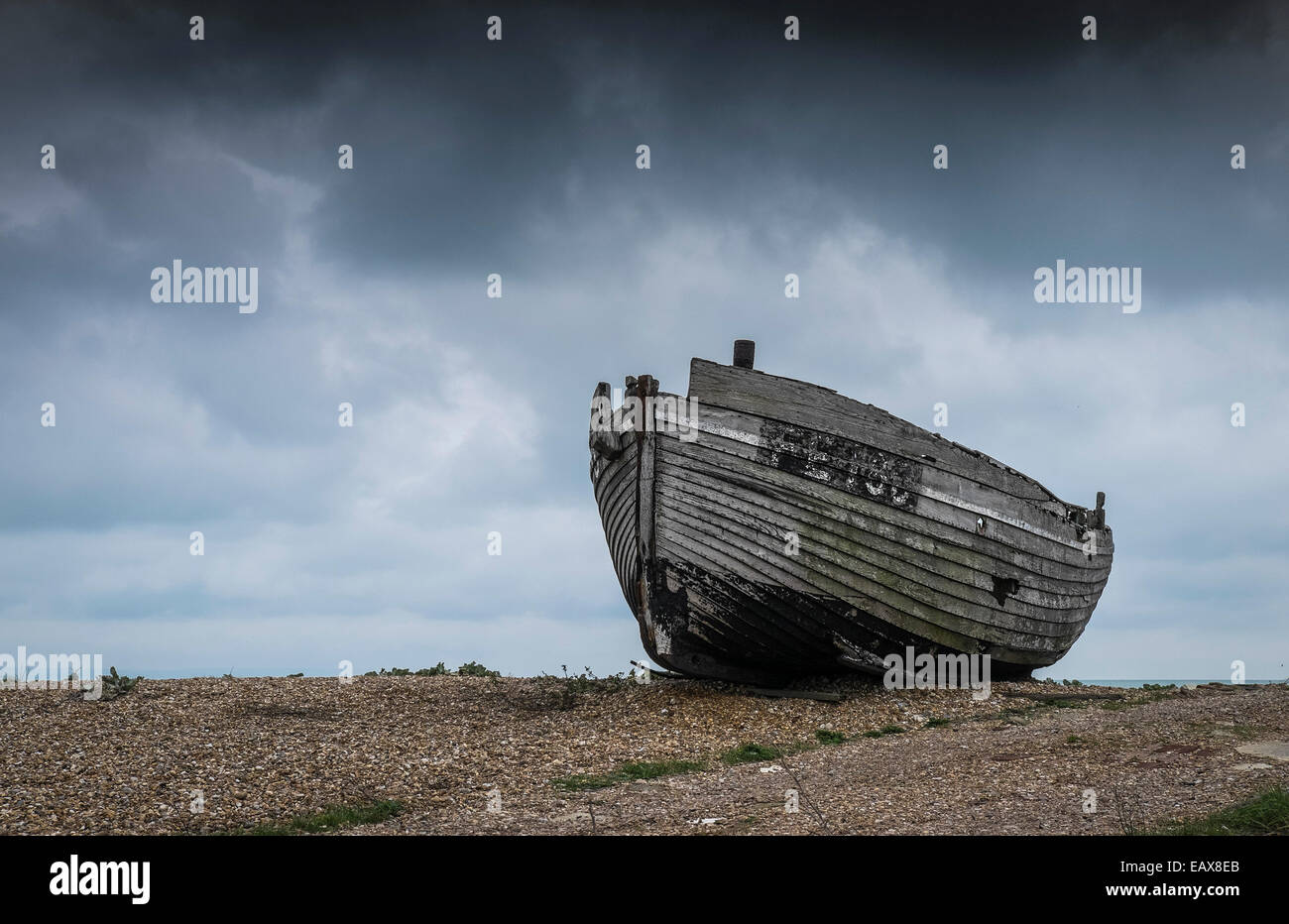 A wooden fishing boat abandoned on the beach at Dungeness in Kent Stock ...