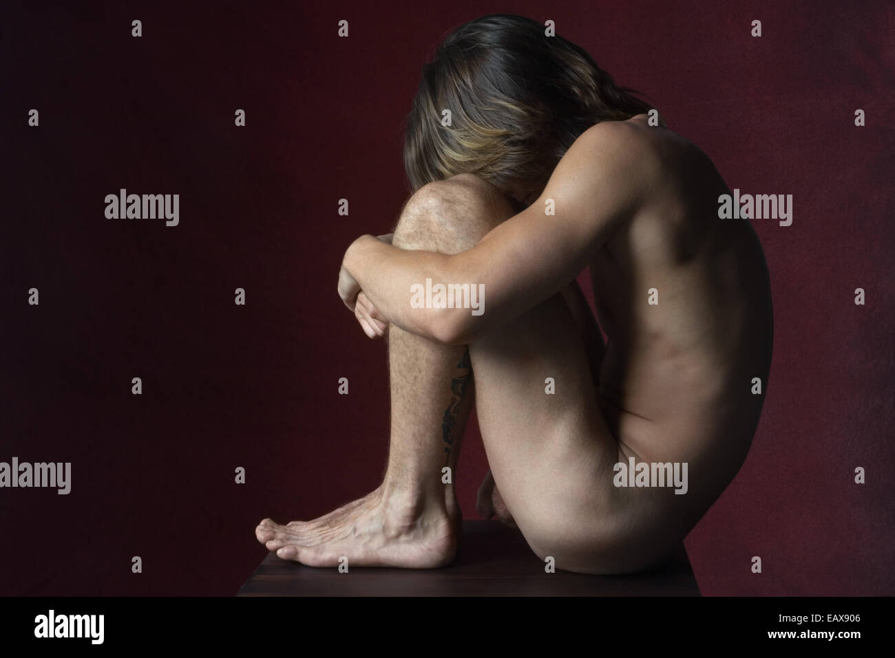 Nude man sitting in fetal position, side view Stock Photo