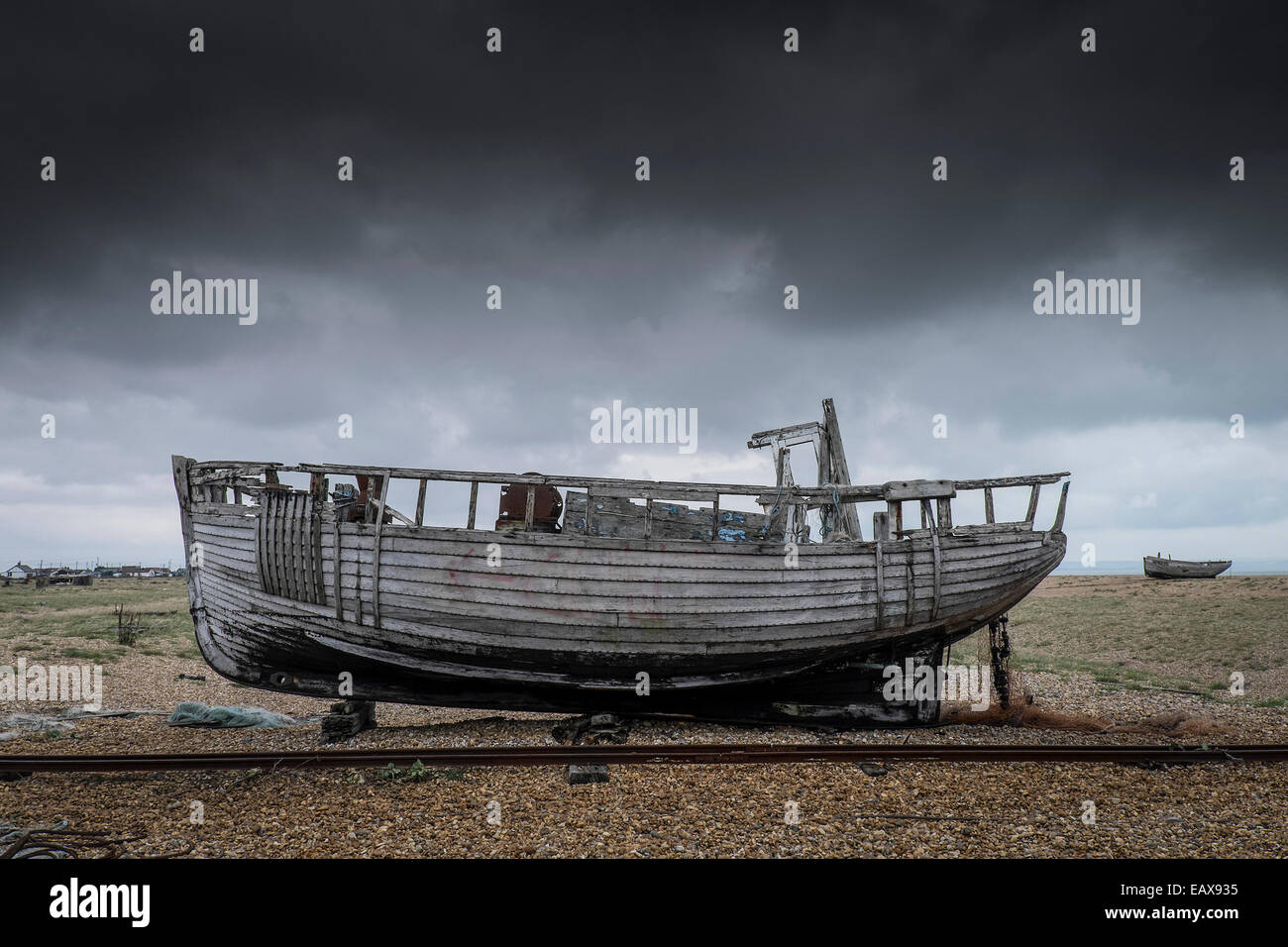 An old wooden fishing boat abandoned on the beach at Dungeness in Kent ...