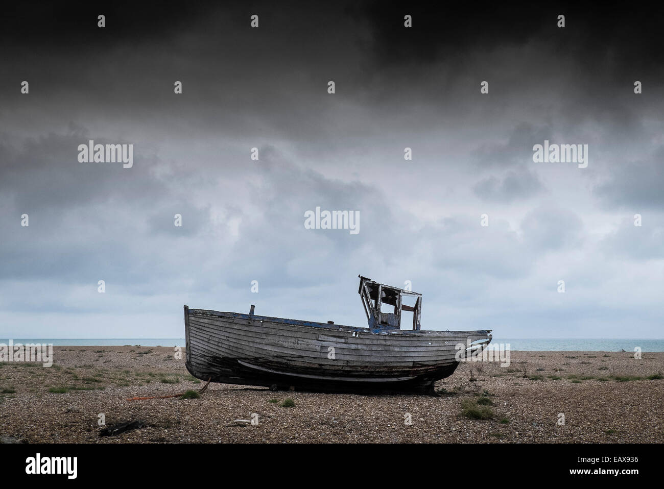 An old wooden fishing boat abandoned on the beach at Dungeness in Kent ...