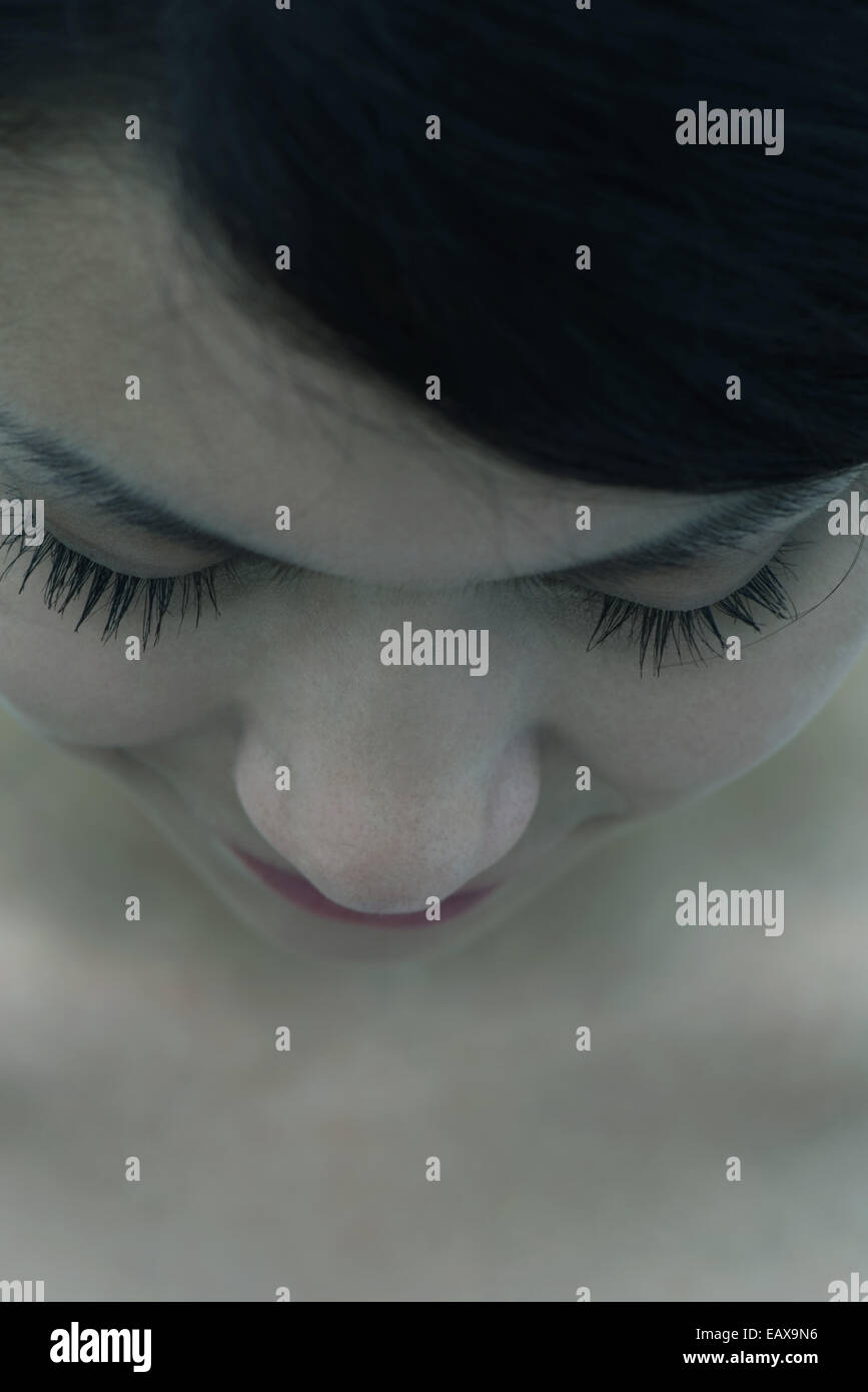 Young woman with head down and eyes closed, close-up Stock Photo