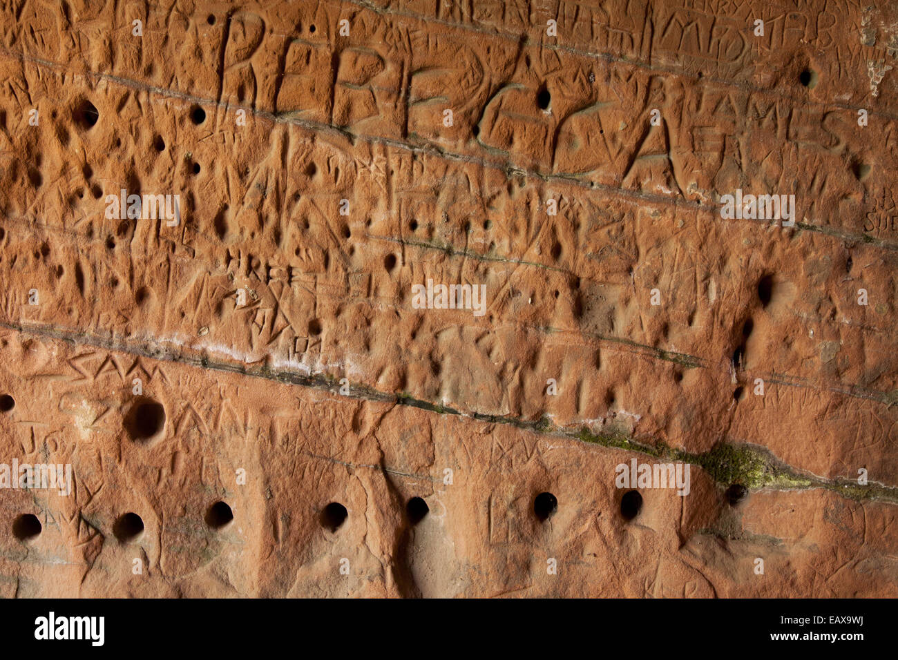 Carved sandstone cave with names and graffiti, showing the clear strata within the rock, Kinver Edge, Shropshire, UK Stock Photo