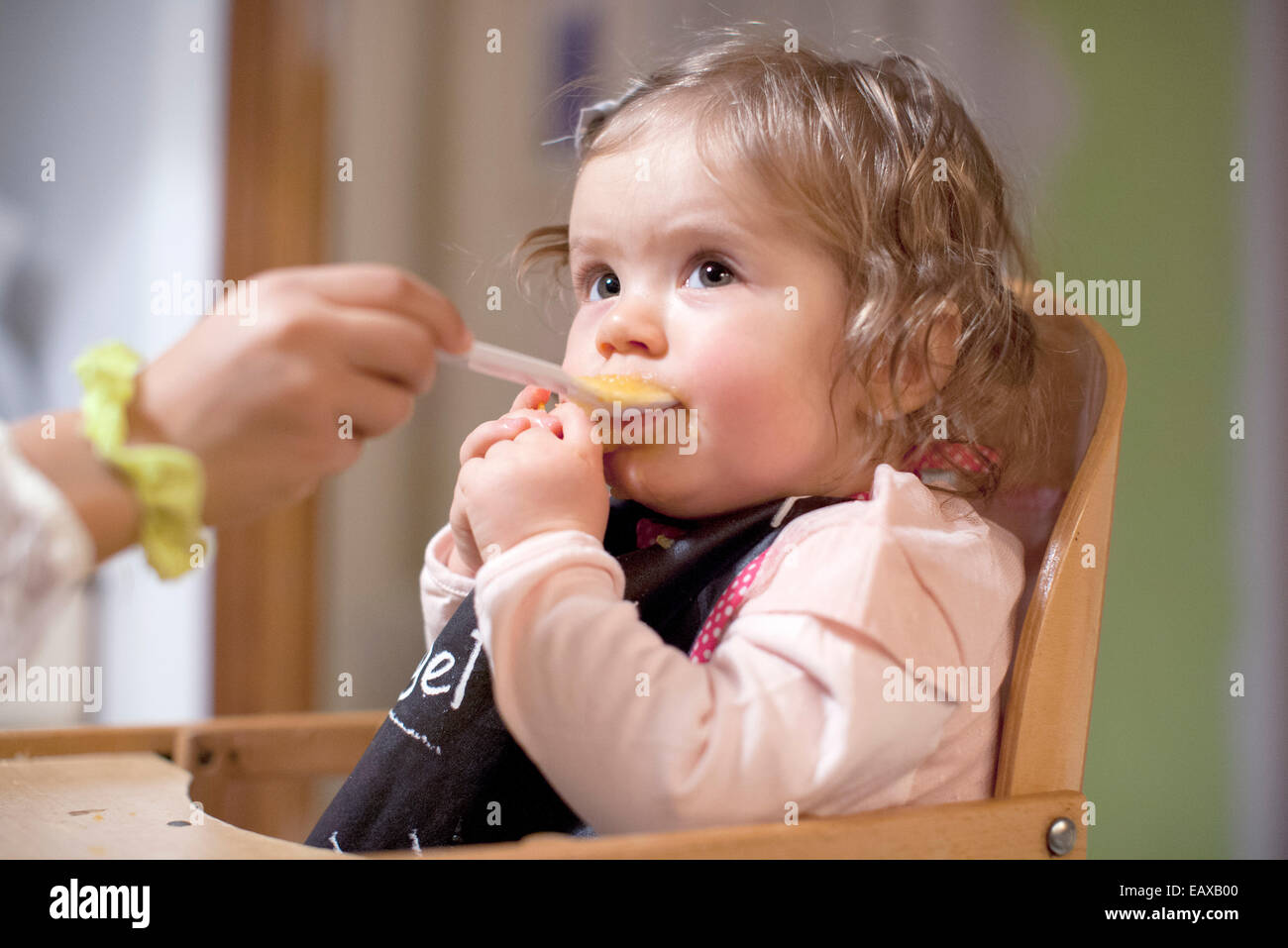 Baby girl being fed by parent, cropped Stock Photo