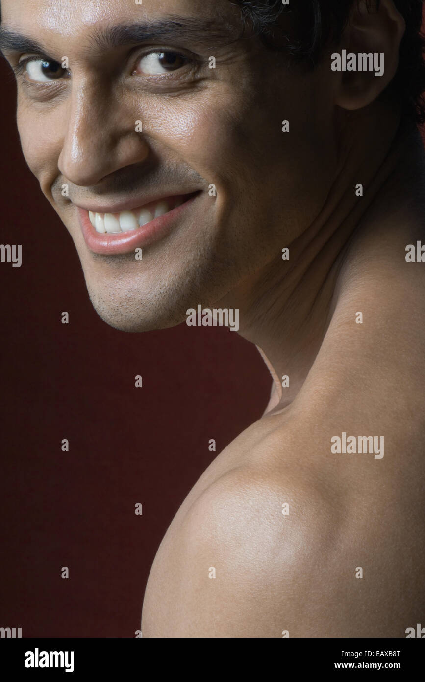 Nude man smiling over shoulder at camera, portrait Stock Photo