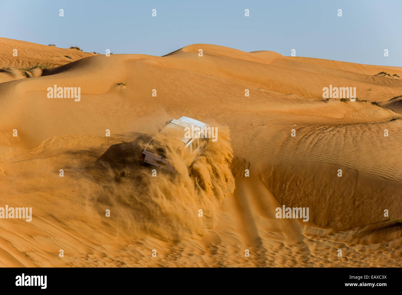 A fourwheel drive jeep driving over sand dunes in the desert of Oman
