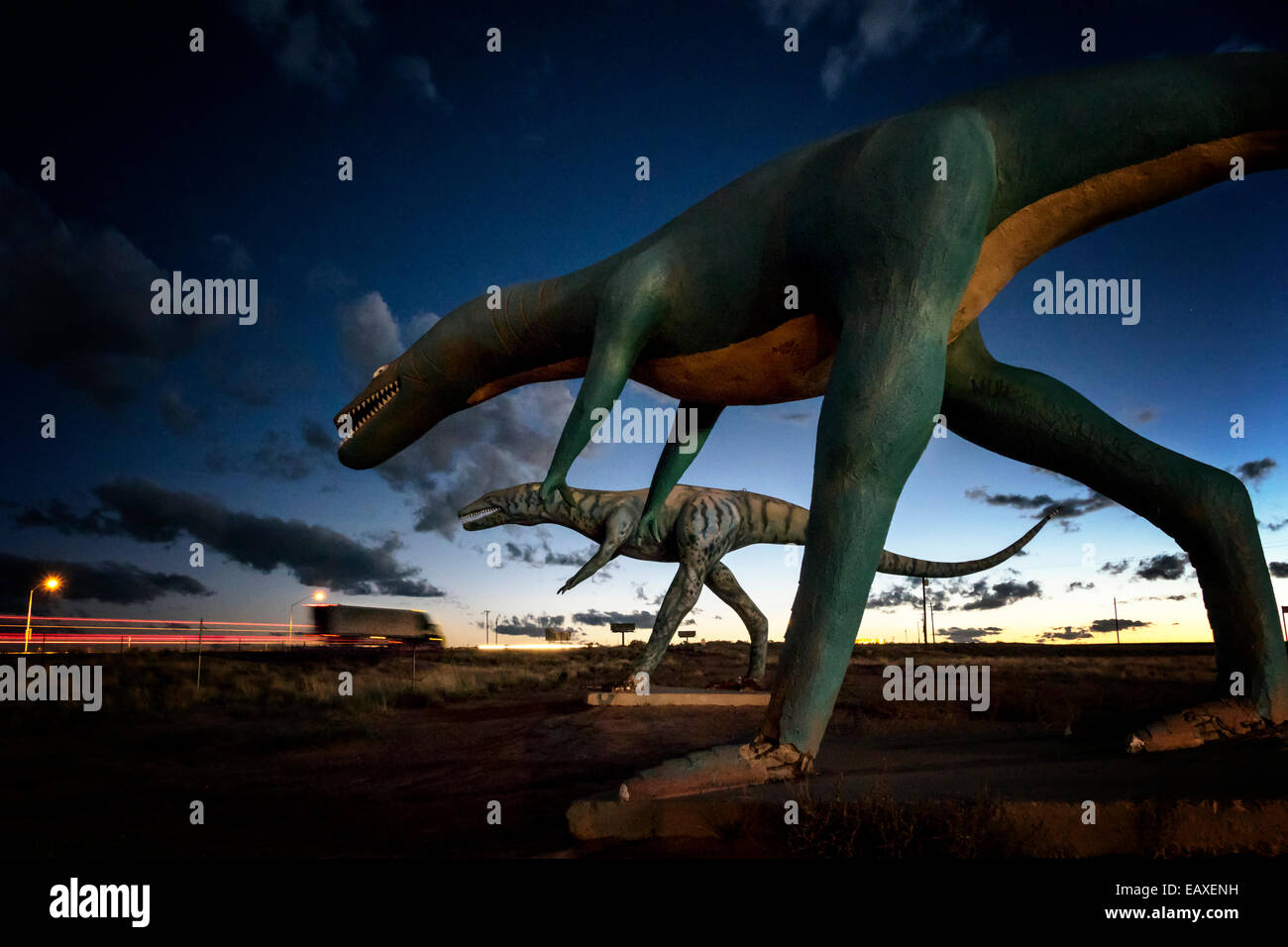 Concrete Dinosaurs along Old Route 66  at sunset,while trucks streak by on I-40. Stock Photo