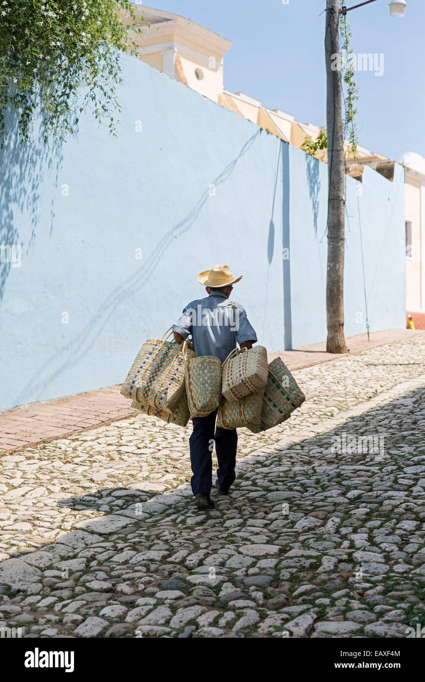 TRINIDAD, CUBA - MAY 8, 2014: Peddler of straw baskets on cobblestone street of Trinidad Stock Photo