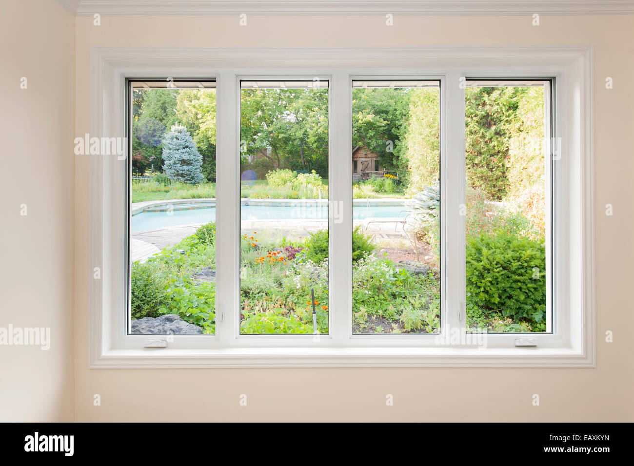 Large four pane window looking on summer backyard with pool and garden Stock Photo