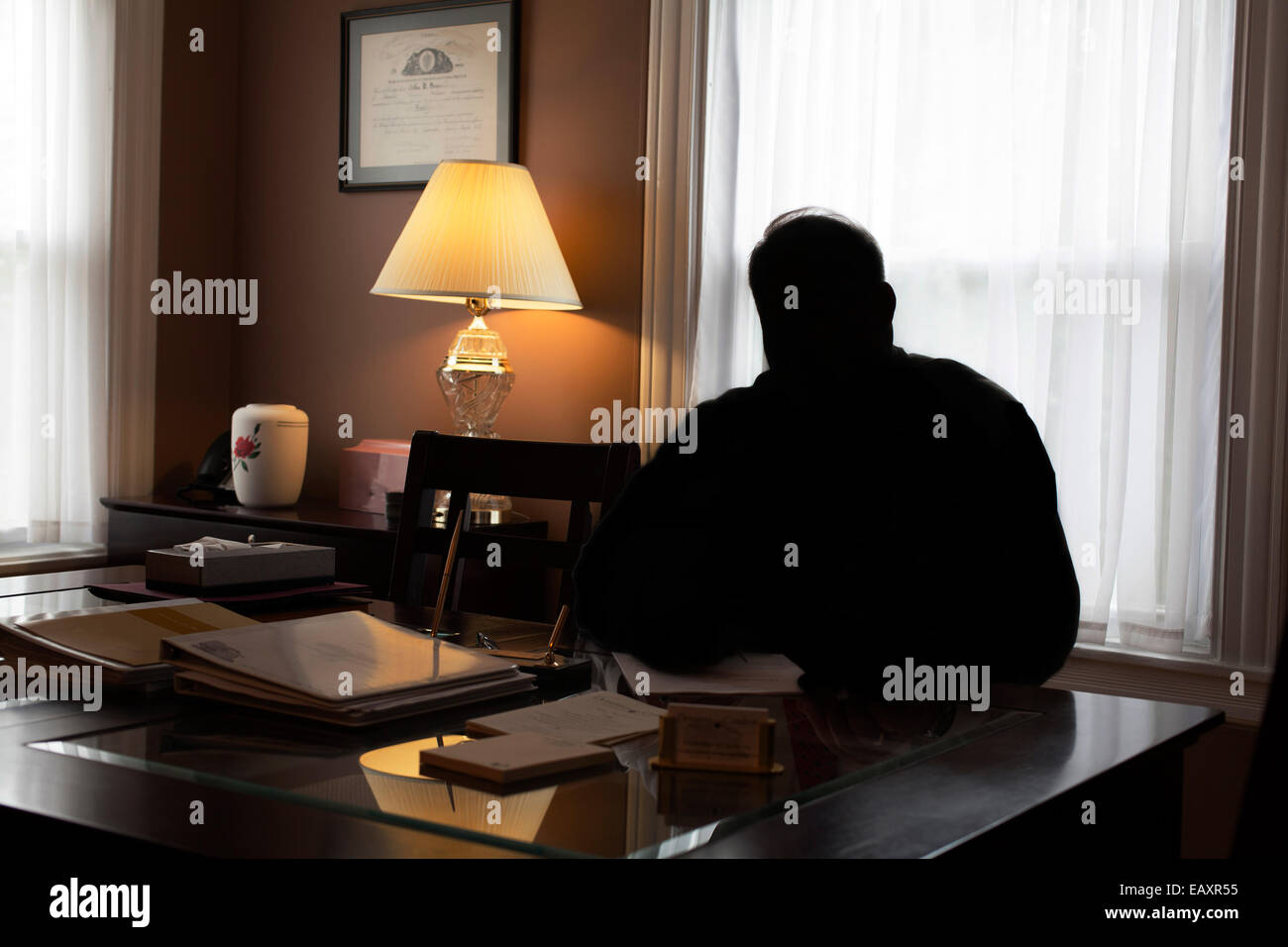 Silhouette of business man at his desk in small office. Stock Photo