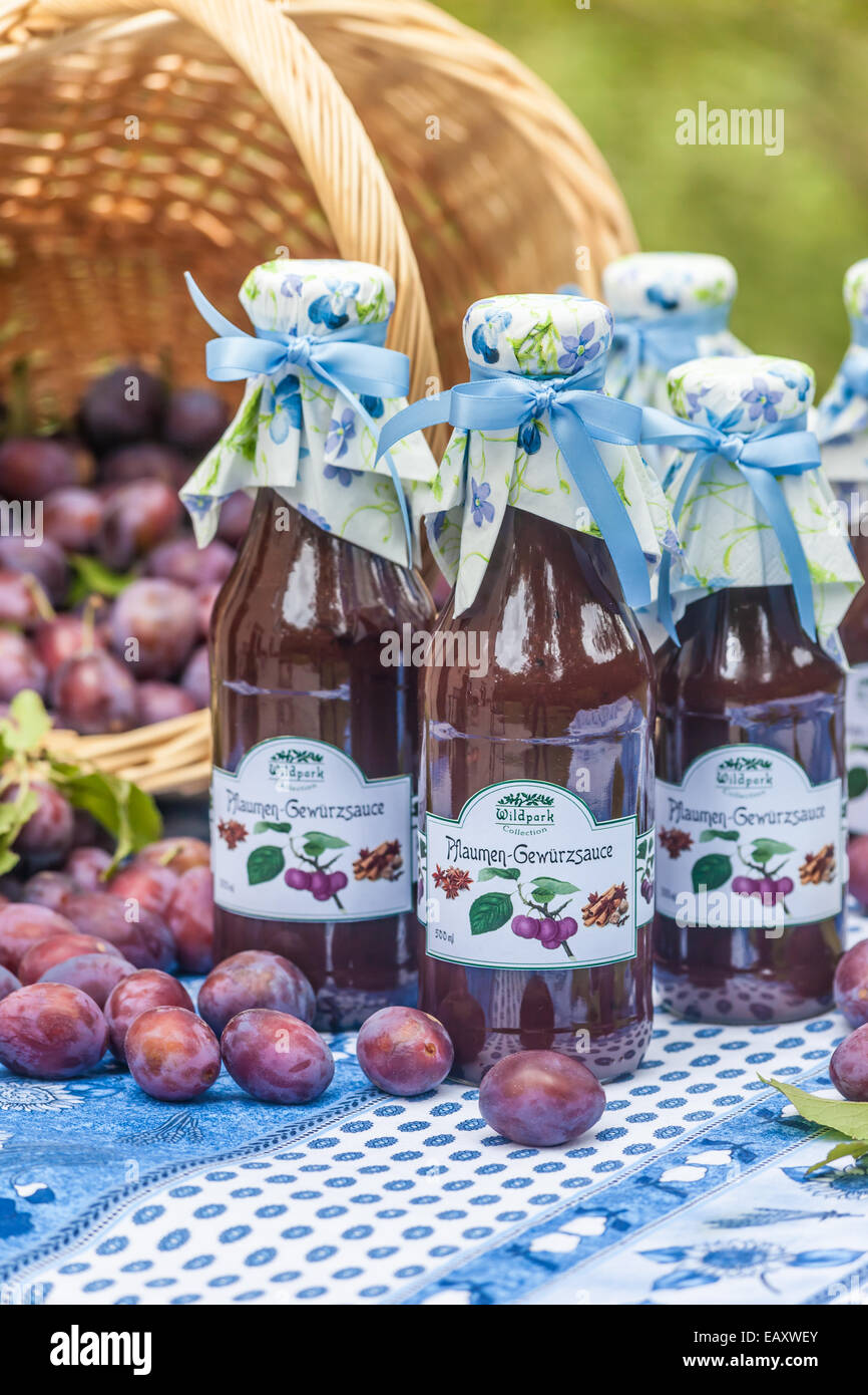 Bottles with  spicy plum sauce on garden table Stock Photo