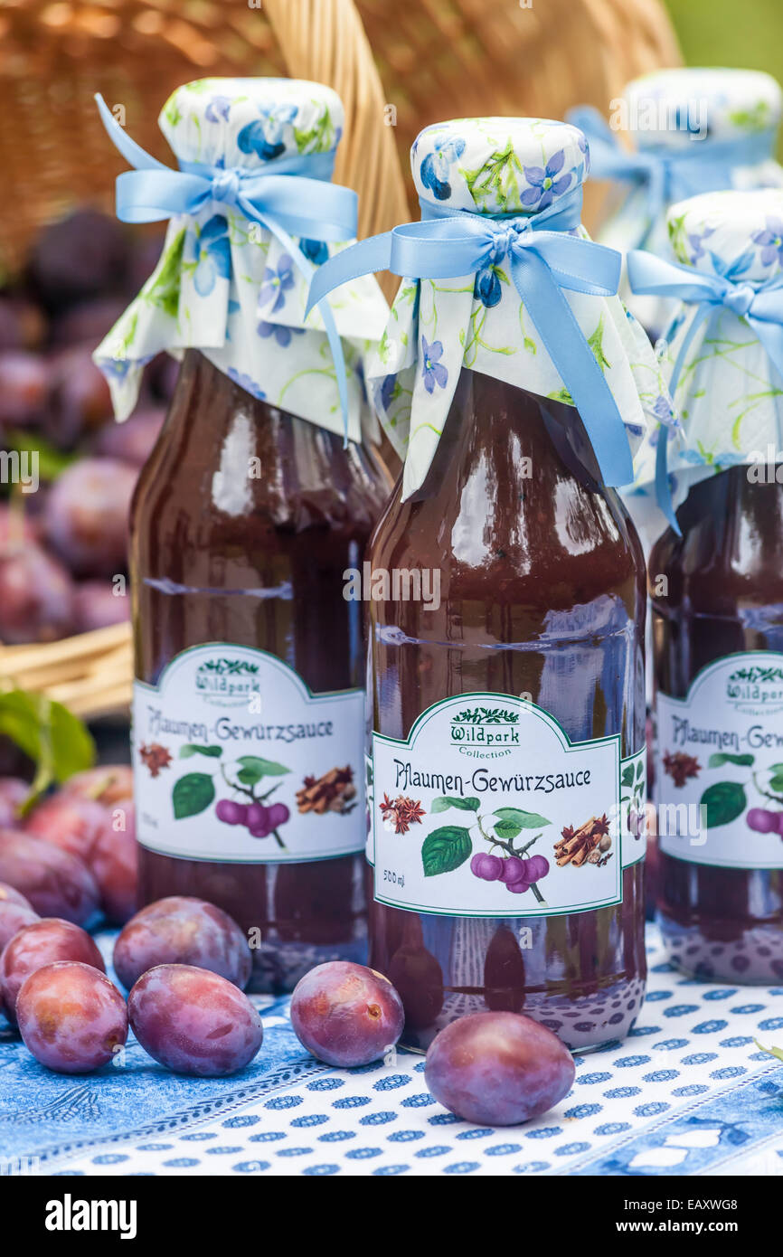 Bottles with  spicy plum sauce on garden table Stock Photo
