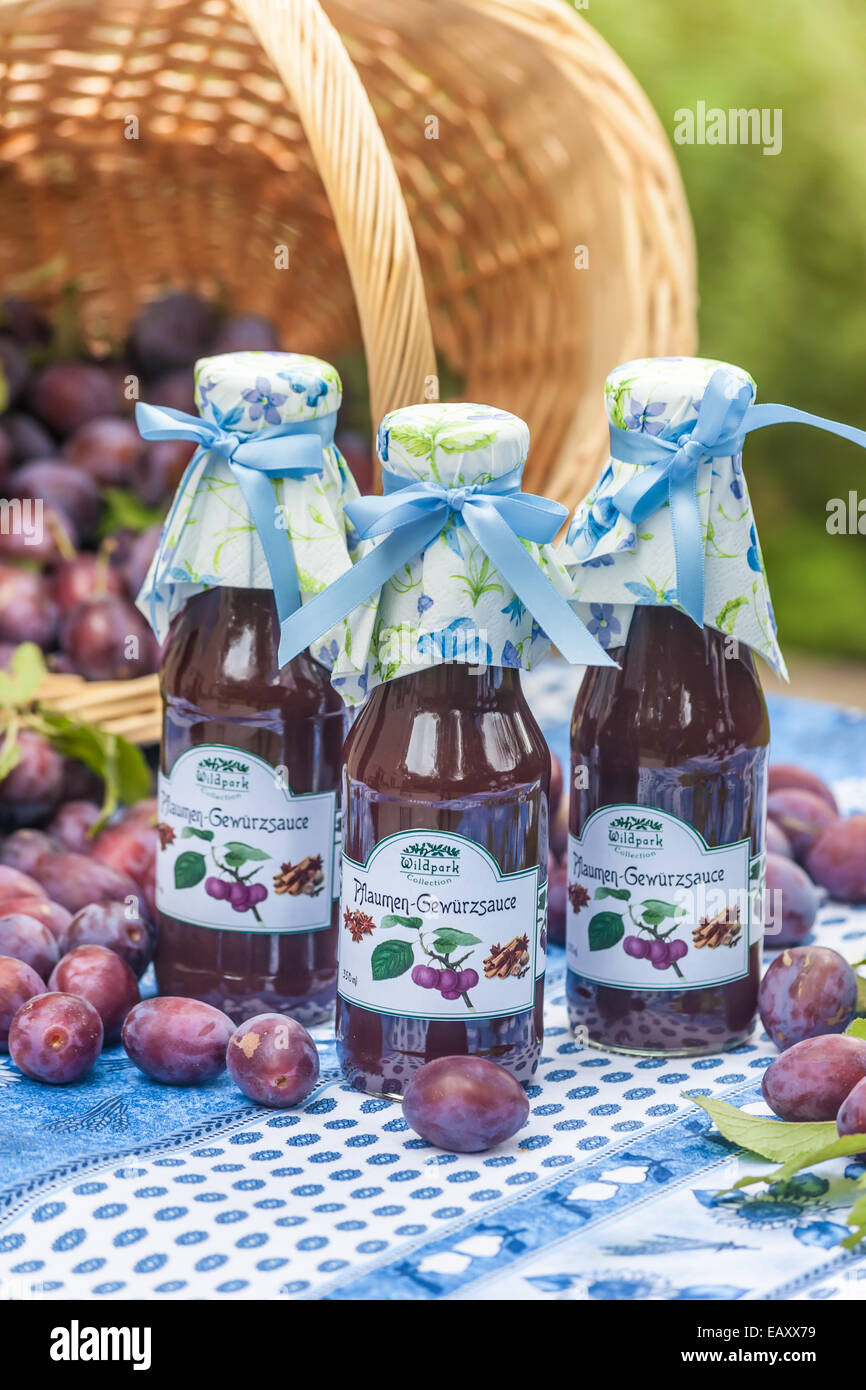 Bottles with  spicy plum sauce on garden table Stock Photo