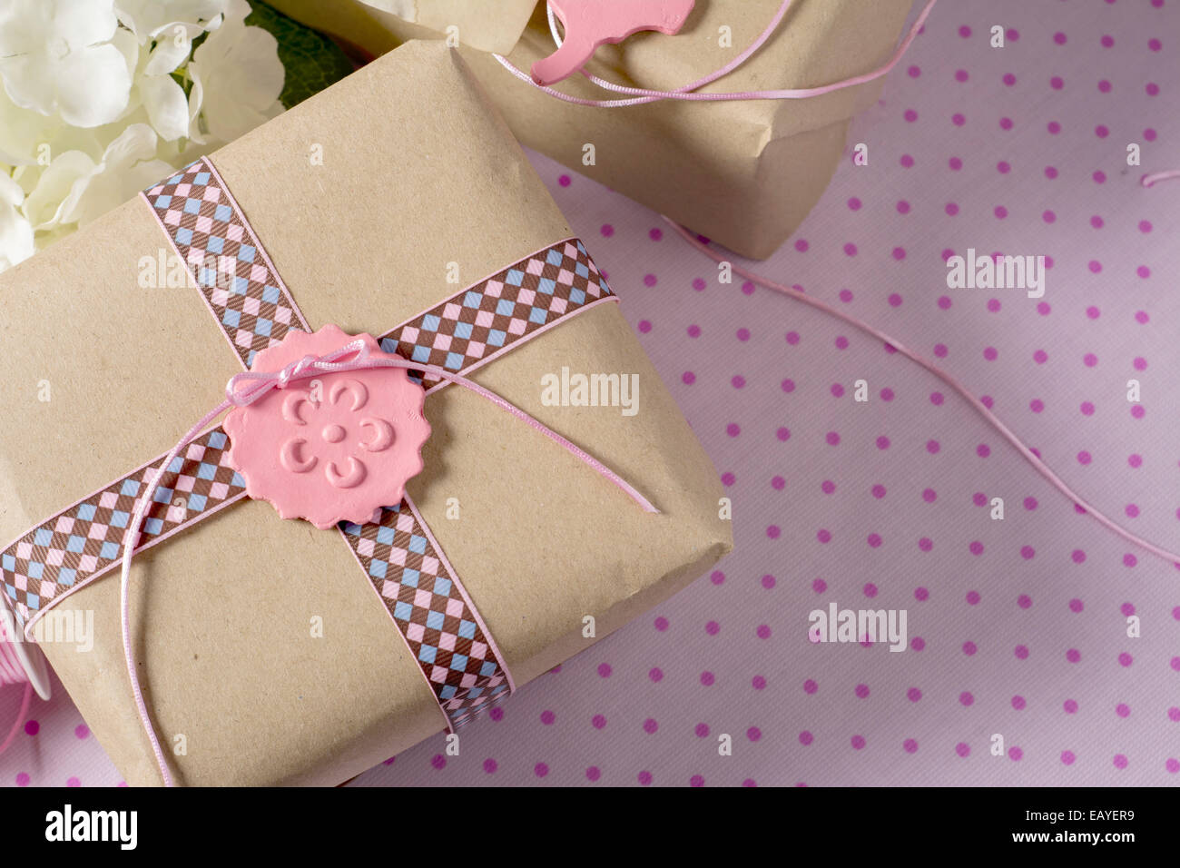 Gift wrapped in recyclable paper, ribbons and label flower on pink
