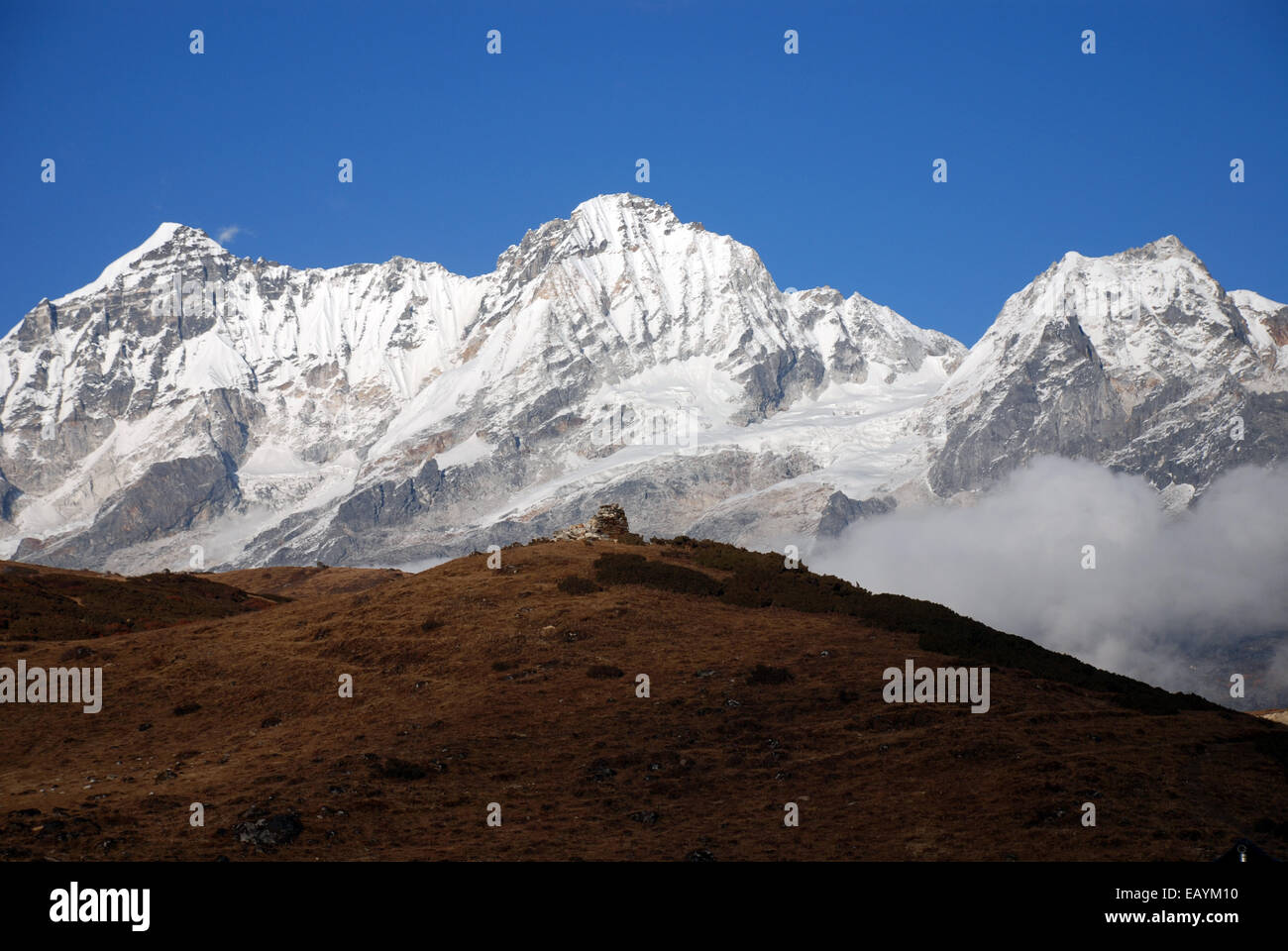 the snow capped peaks of the high Himalayas rise behind the ifoothills of the Singalila ridge in the Indian state of Sikkim Stock Photo