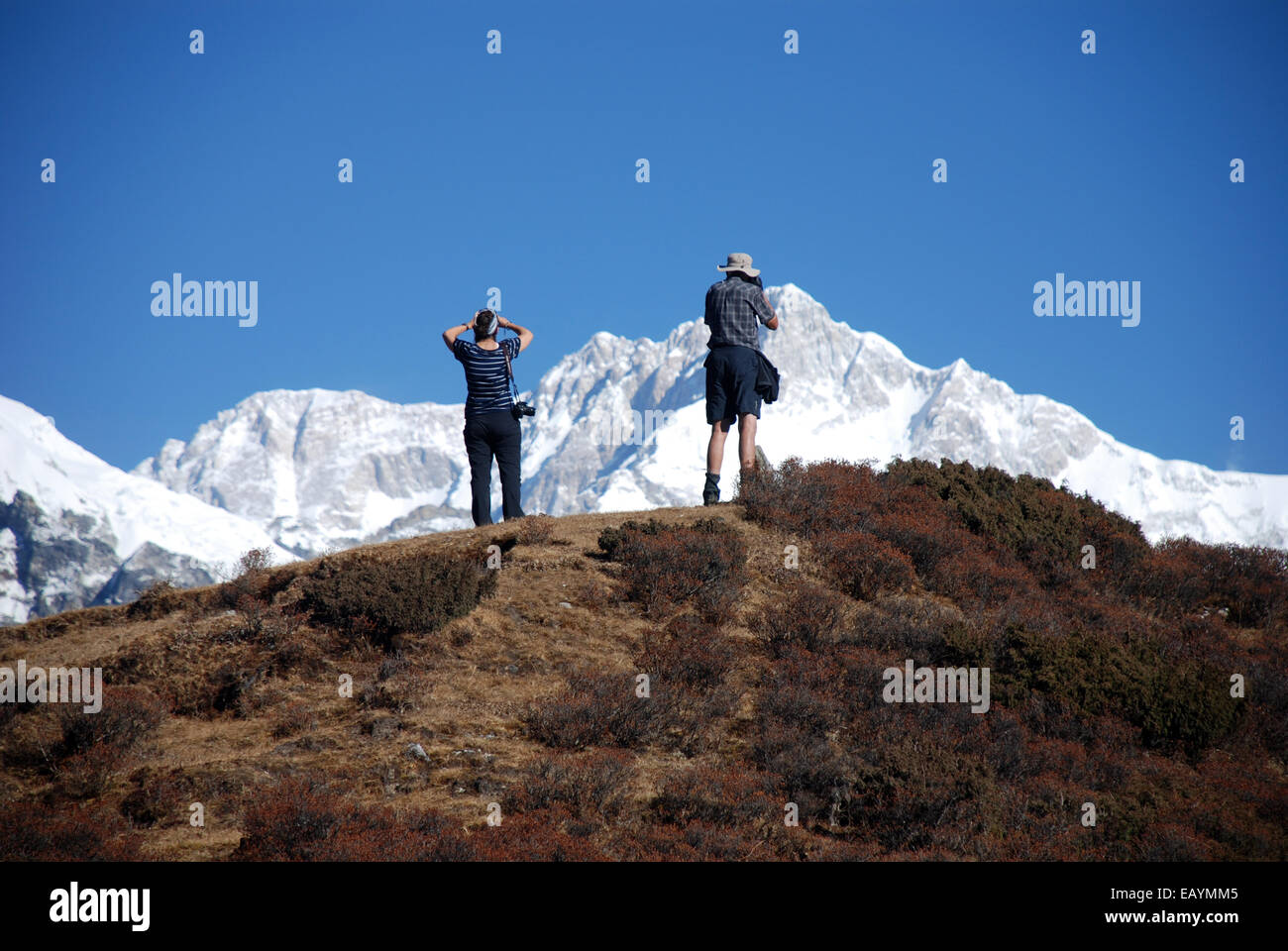 two trekkers photograph he peak of kangchenjunga from a high point on the Singalila ridge Stock Photo
