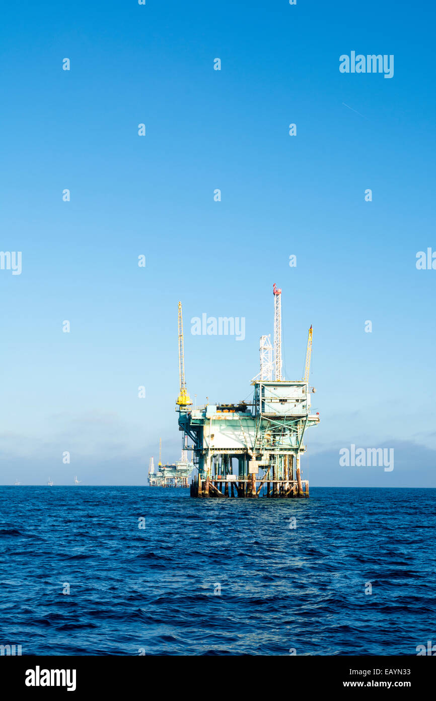 An offshore oil platform rests in deep ocean water on a clear, bright, sunny day. Stock Photo